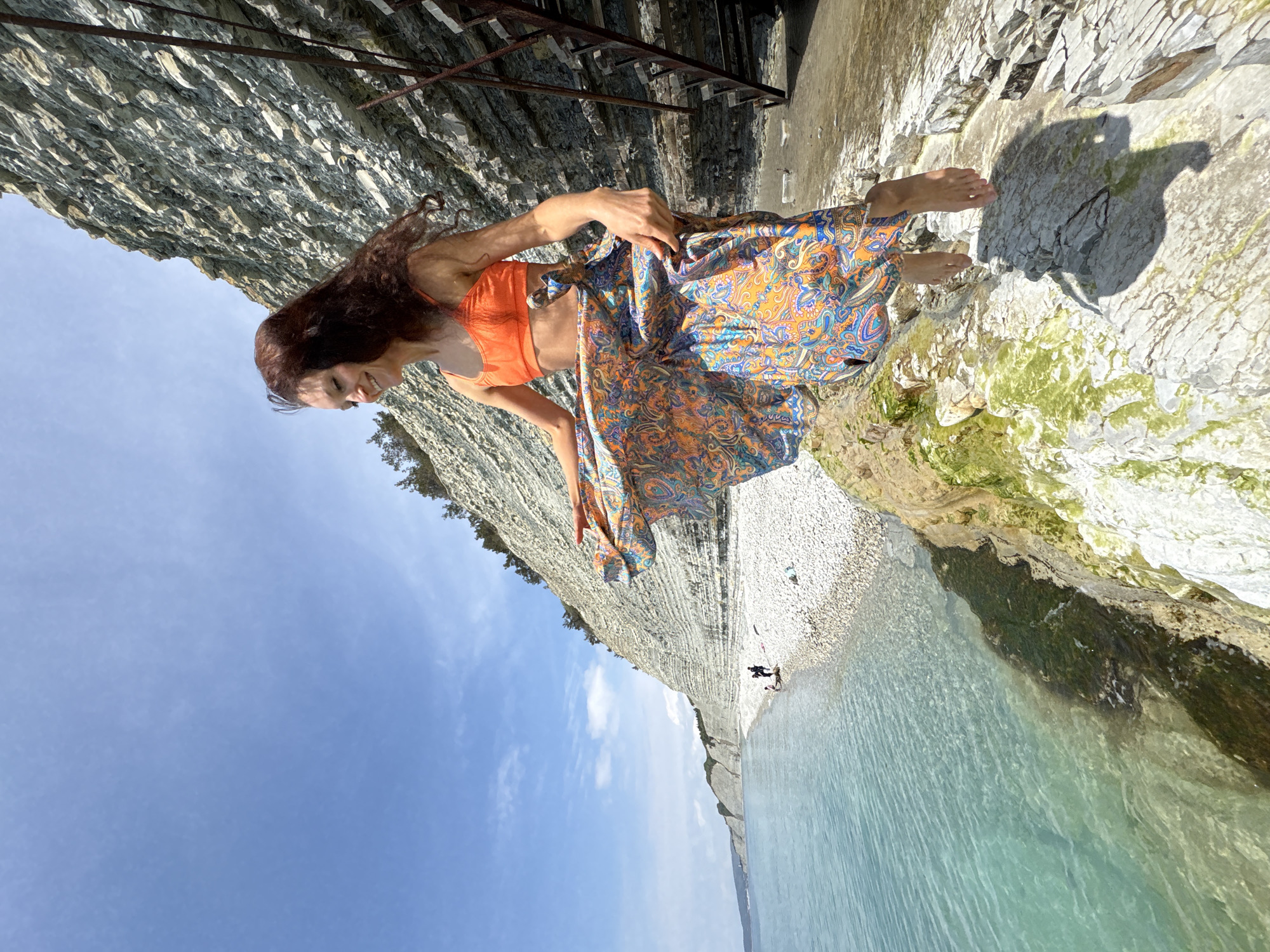 Woman poses for photo on sunny rocky beach