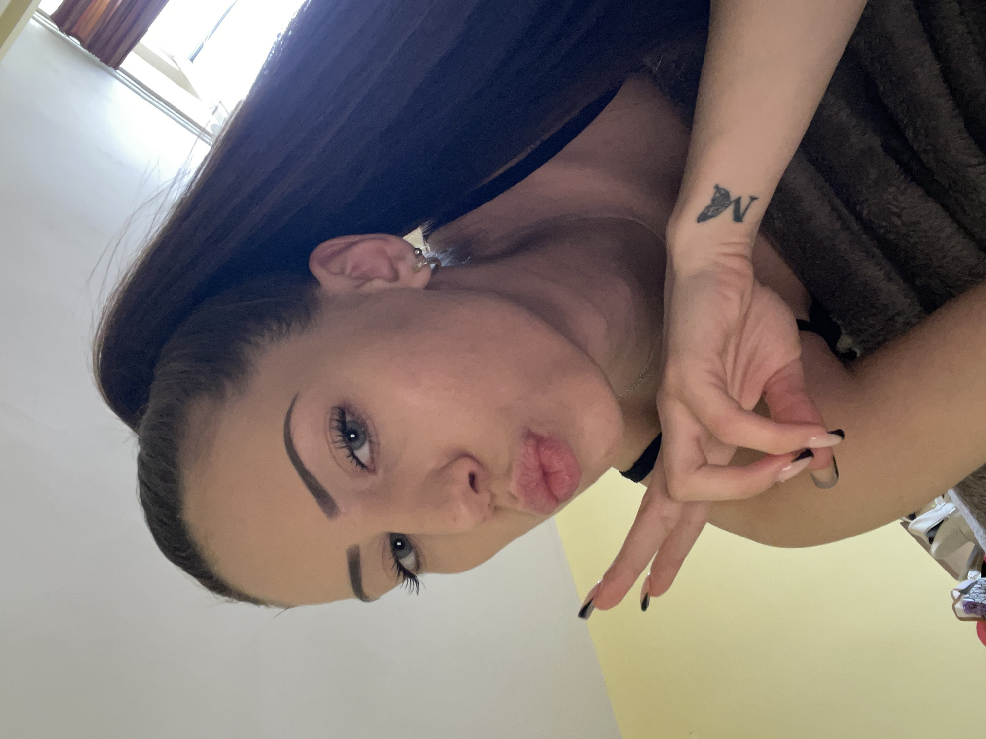 Woman takes selfies indoors, displays wrist tattoo