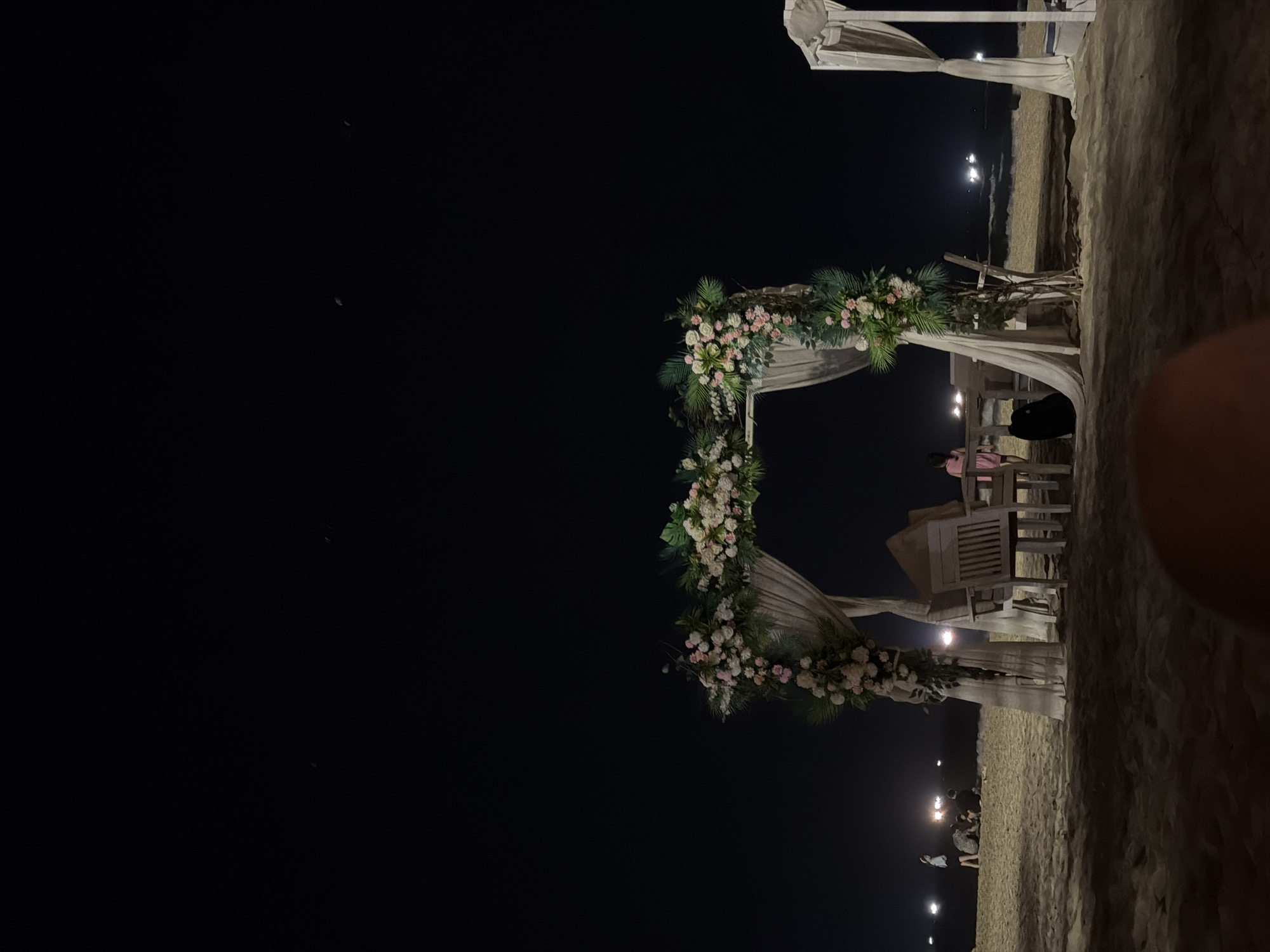 Nighttime beach celebration with floral archway in Đà Nẵng