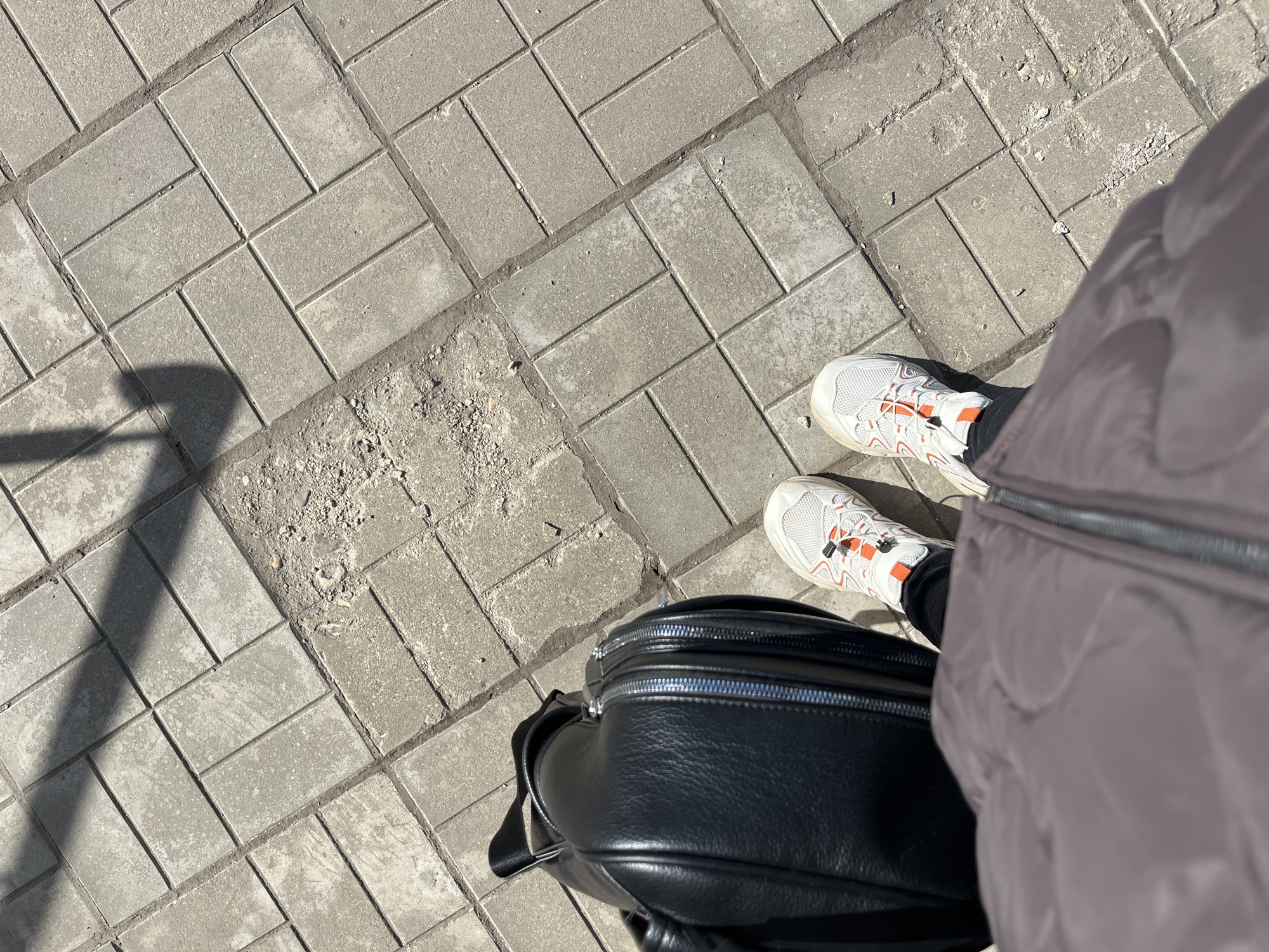 Woman walks damaged sidewalk in Klin, Russia