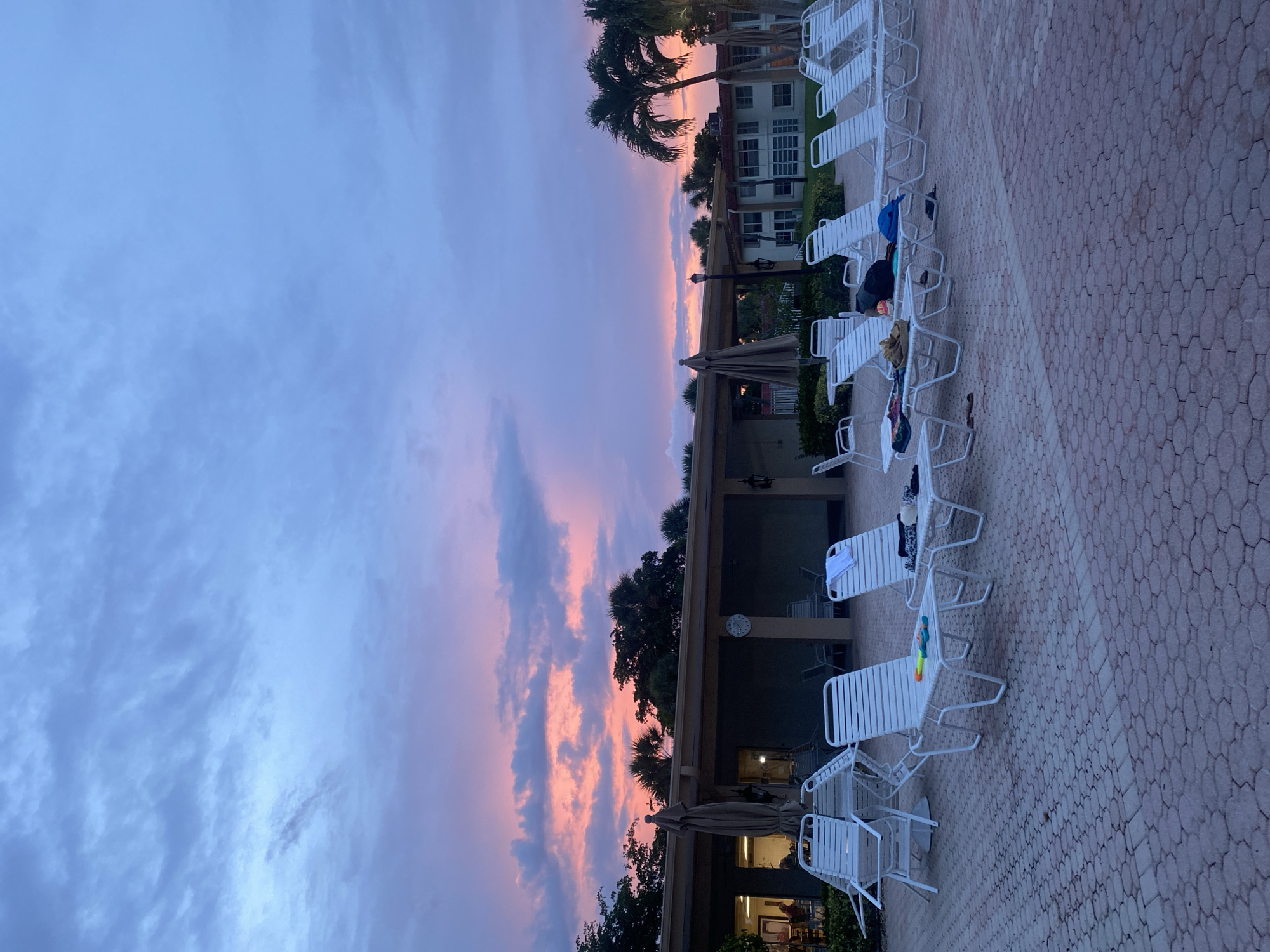 Resort pool at sunset, lounge chairs empty as dusk settles in