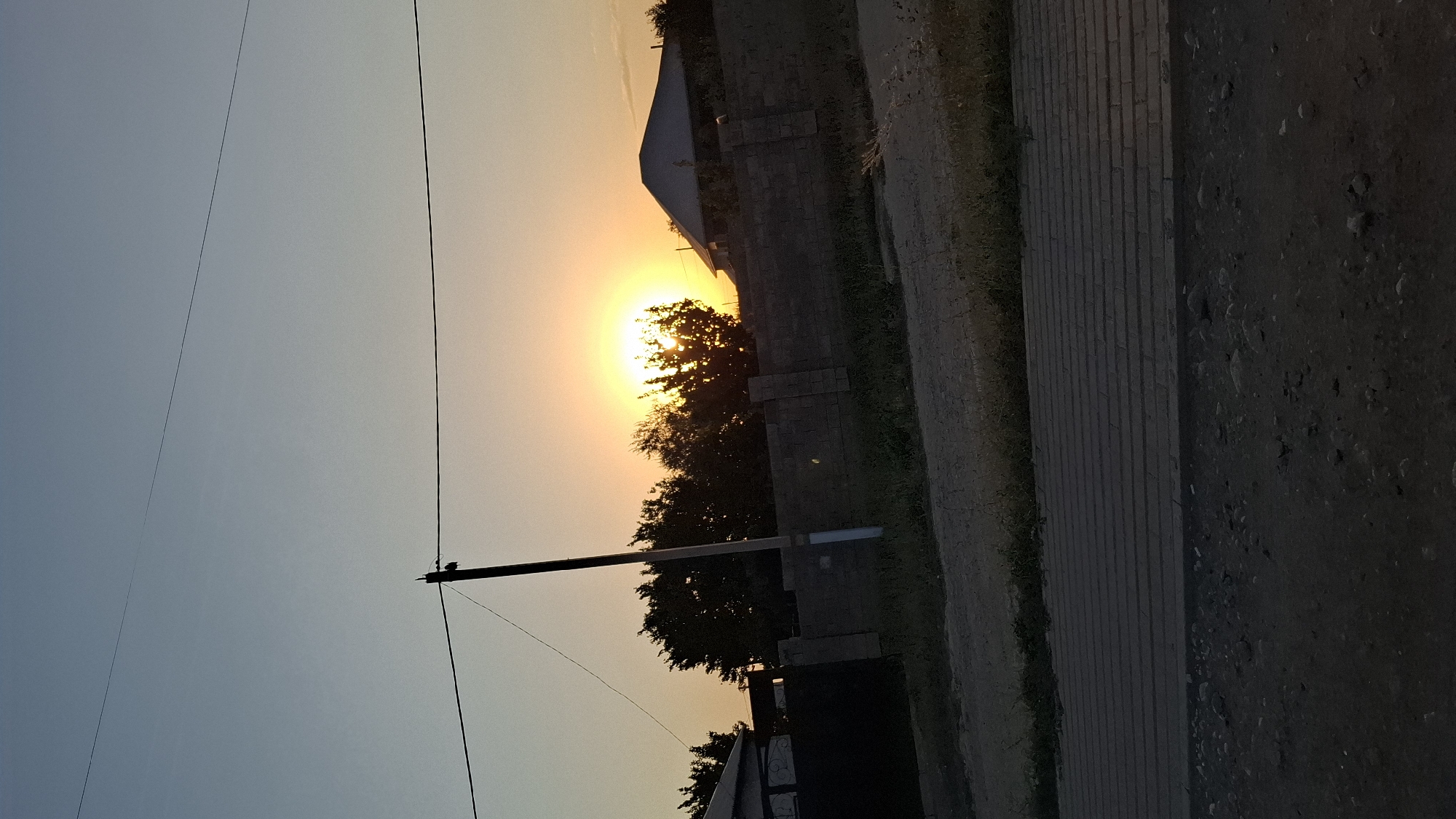 Golden sunset behind trees and brick fence in Shubarssu