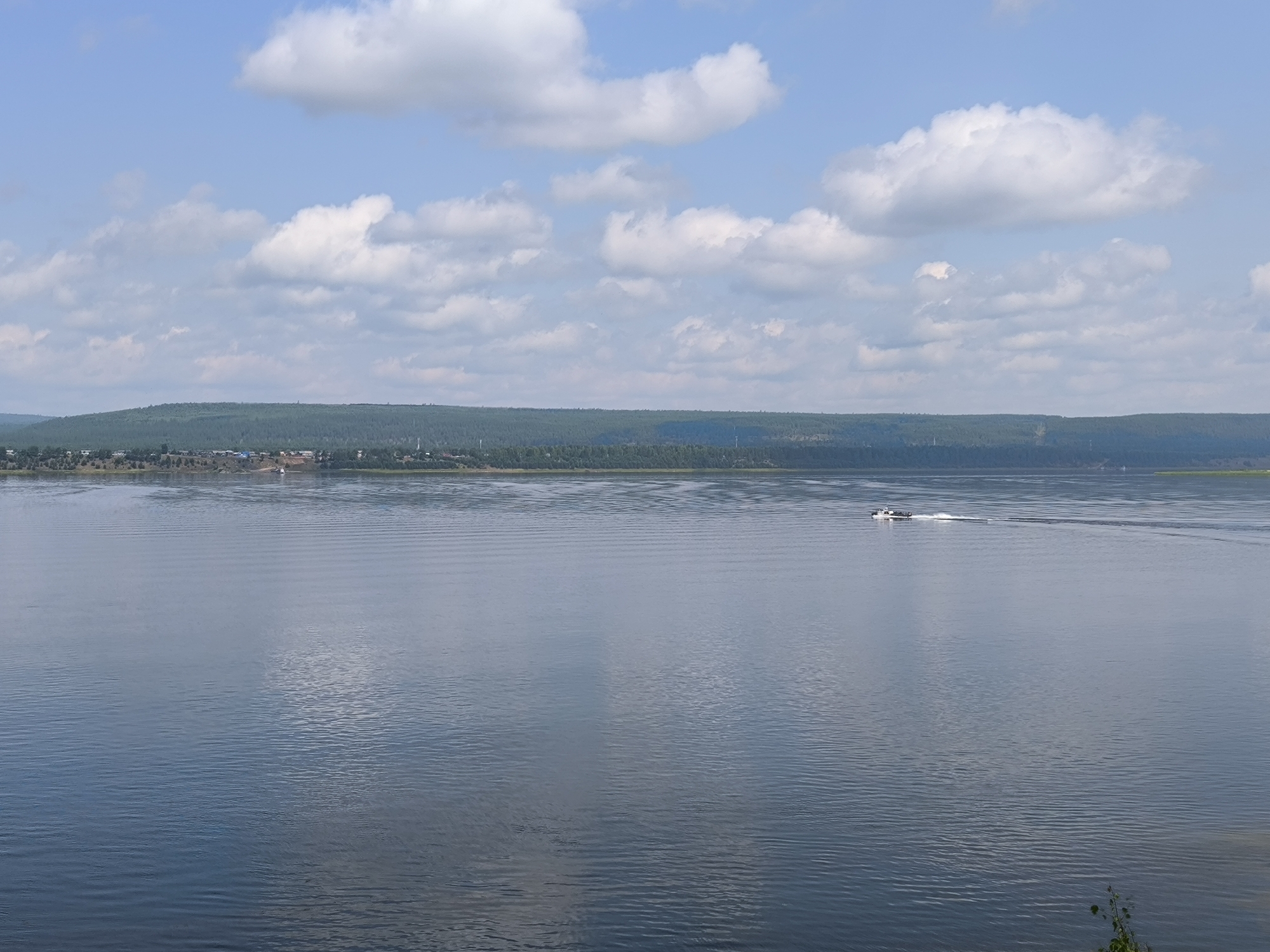 Calm river near Boguchany reflects sky and distant village