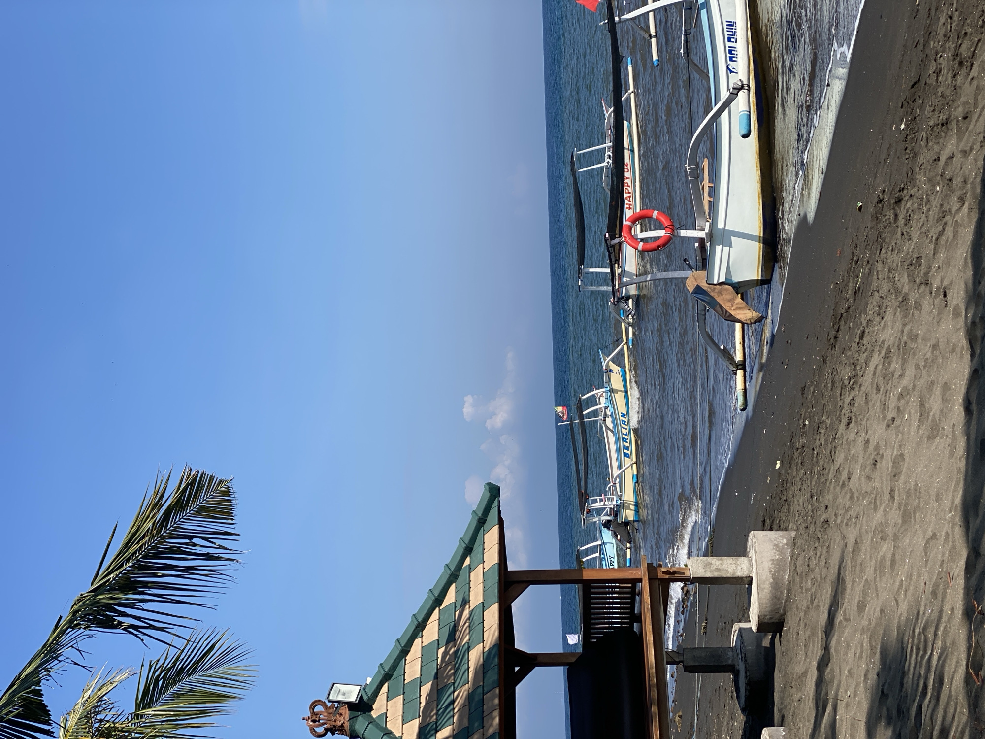 Black sand beach morning in Buleleng, boats and fruit