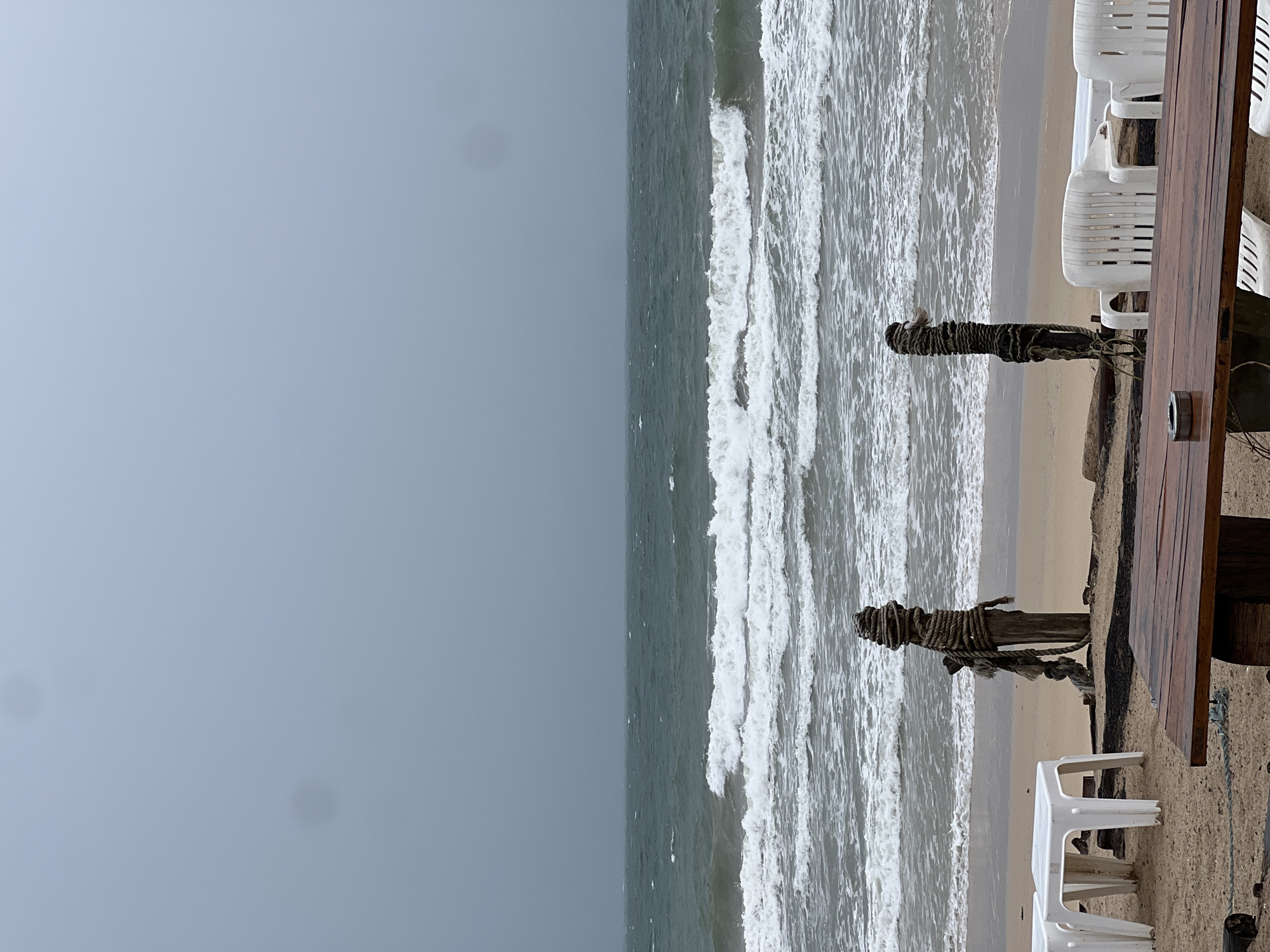 Empty beach under stormy skies with red warning flag flying