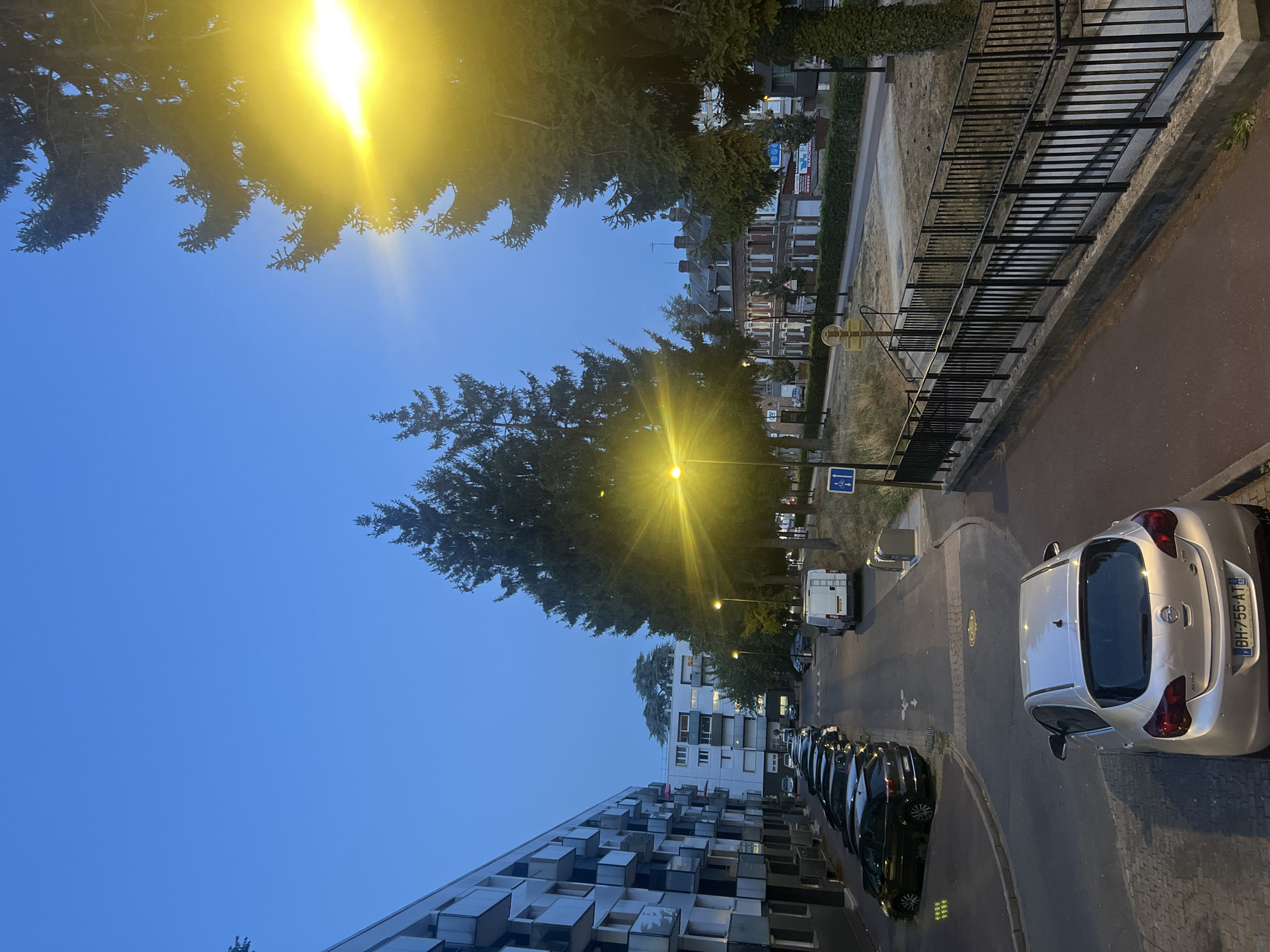 Maromme residential street at dusk, street lamps switching on
