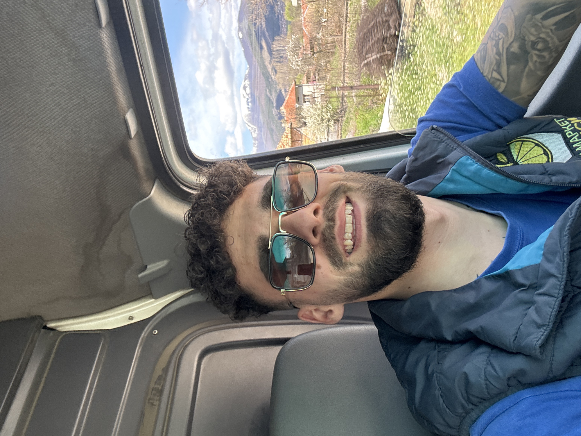 Smiling bearded man observed in vehicle wearing blue clothing