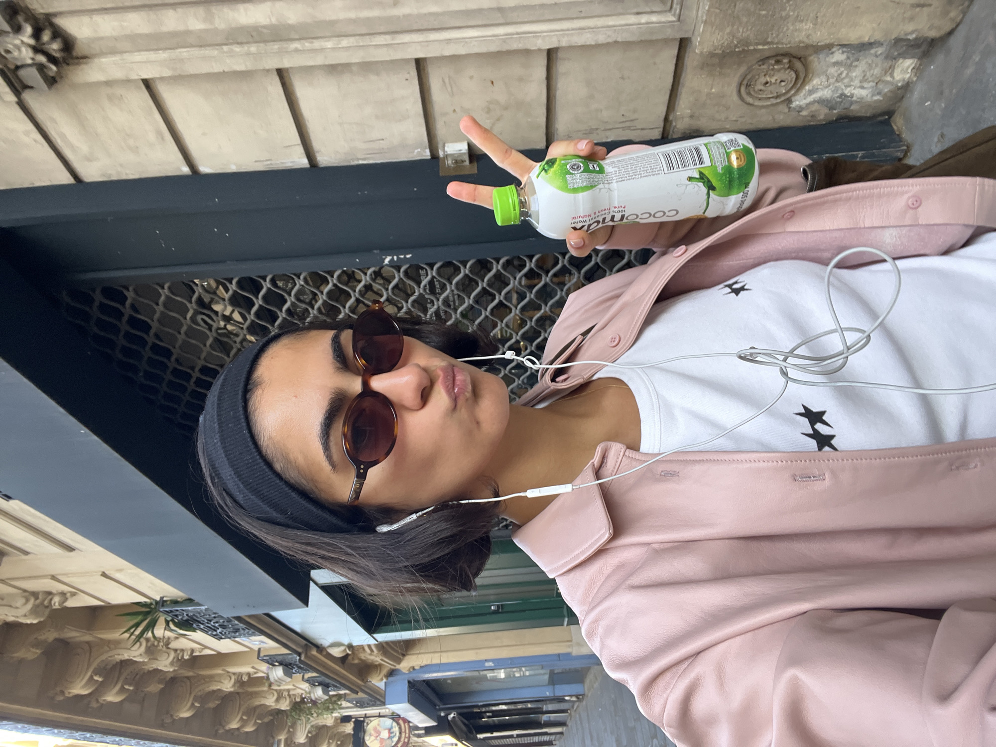 Woman takes selfies on Paris street wearing pink jacket