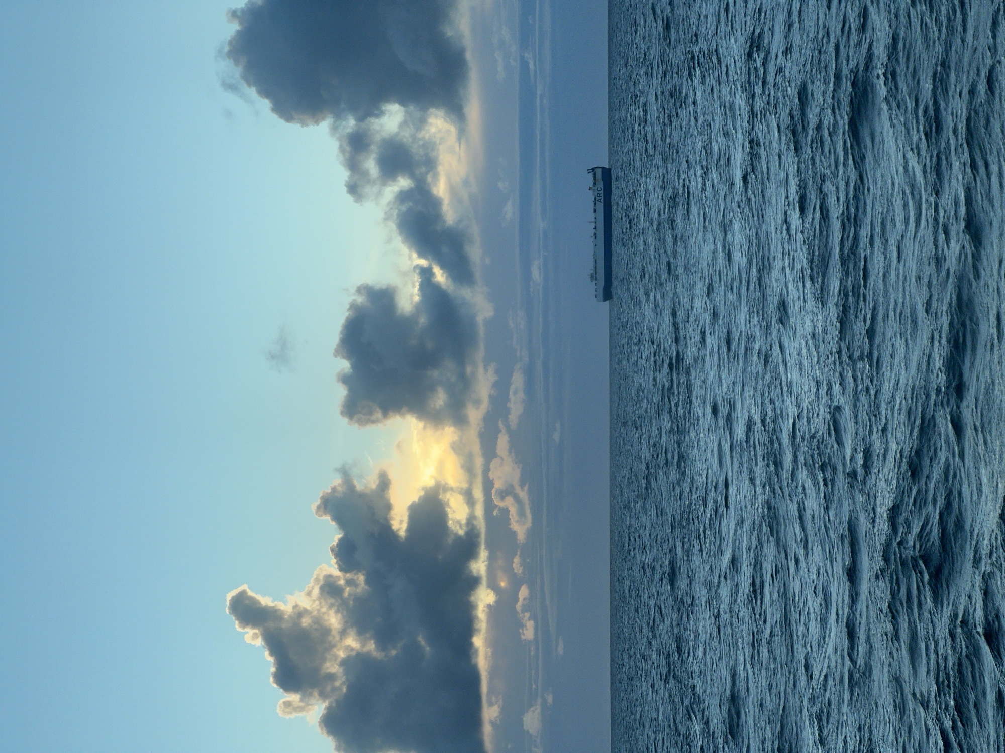 ARC car carrier crosses open sea under a stormy, golden sky