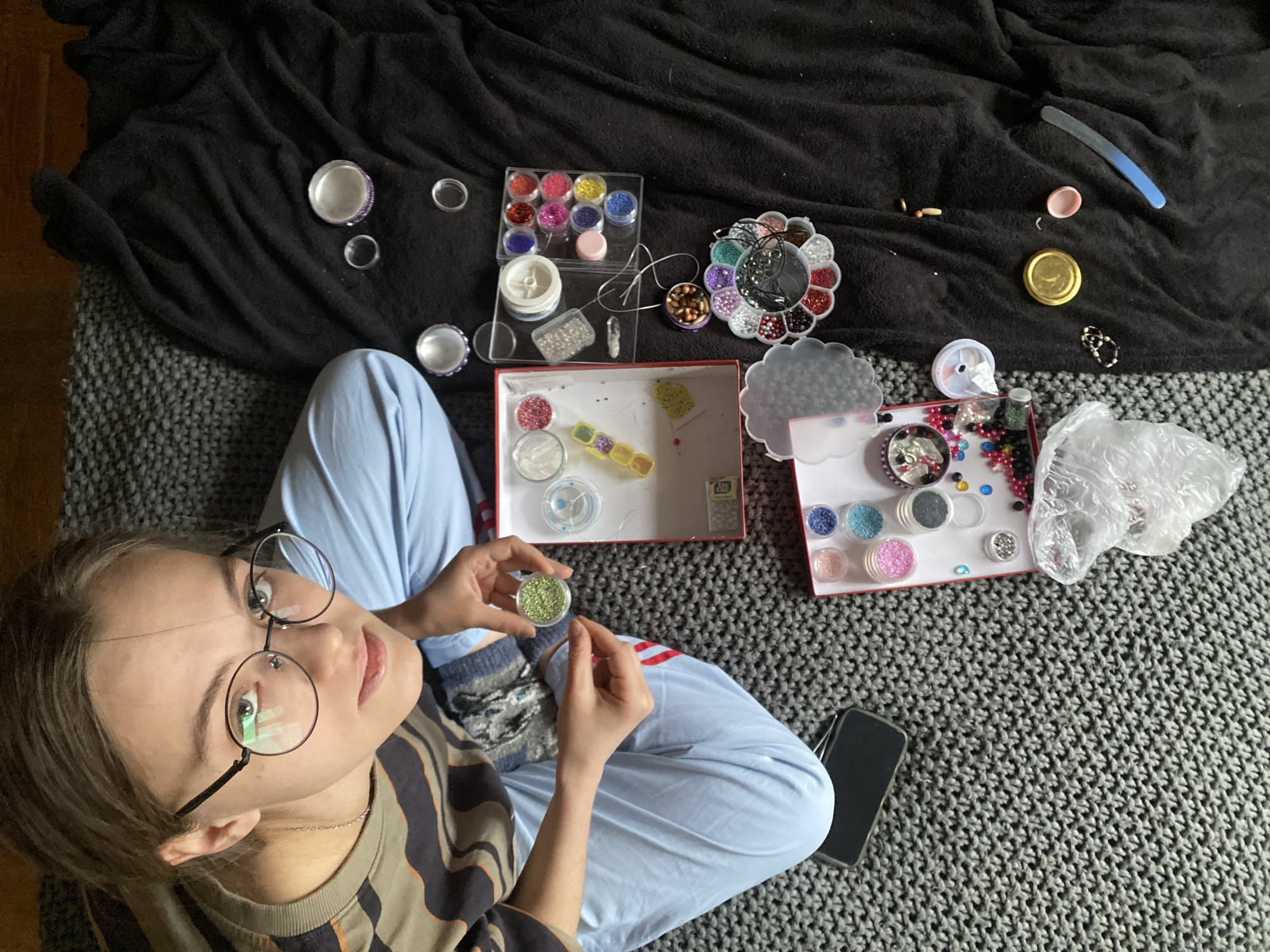 Person crafts beaded lanyard in Moscow park afternoon