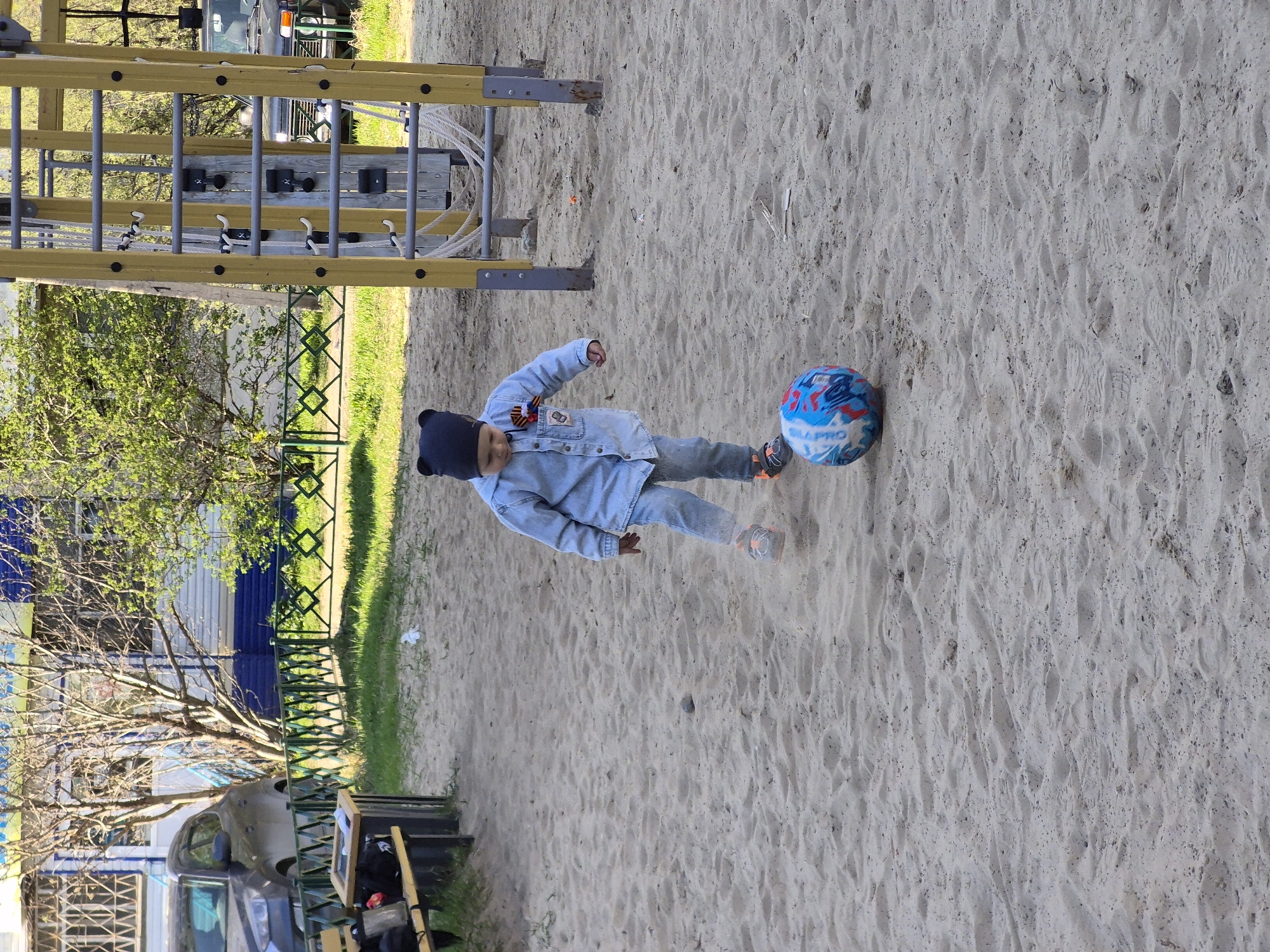 Child plays ball, woman takes selfie in Tobolsk playground area