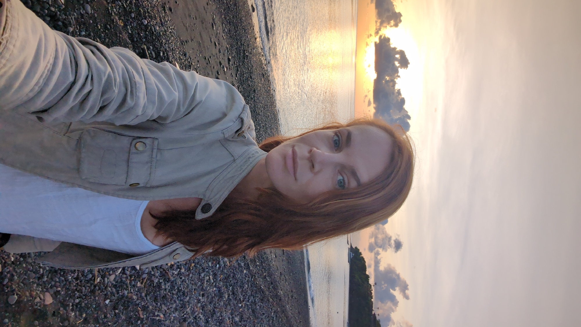 Woman photographs sunset at rocky beach in Abang, Indonesia