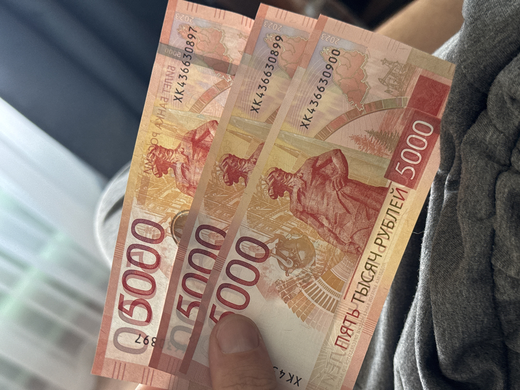 Person holds three 5000-ruble Khabarovsk banknotes in Verkhov'e