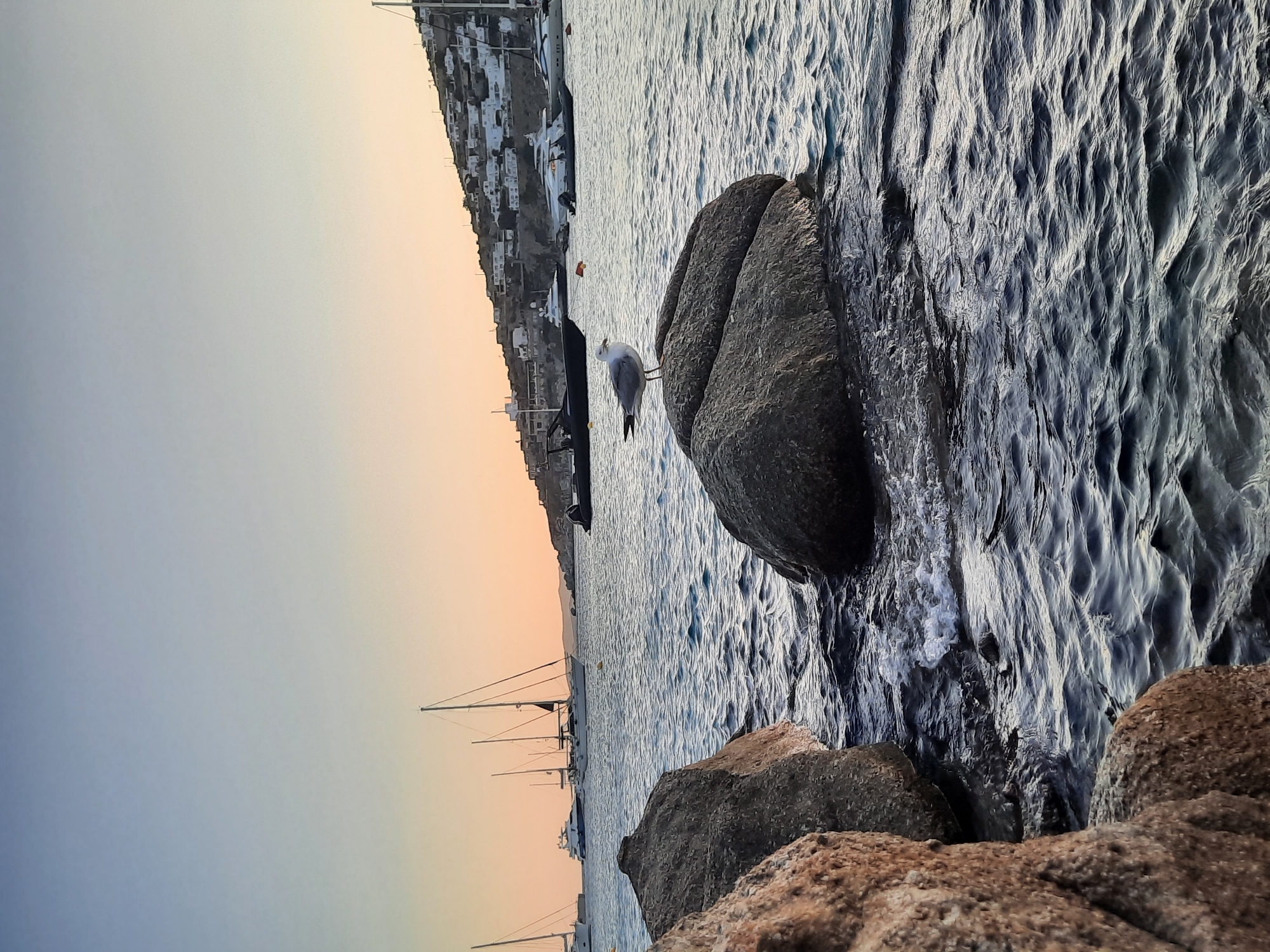 Weathered rocks in calm water at a Greek island sunset
