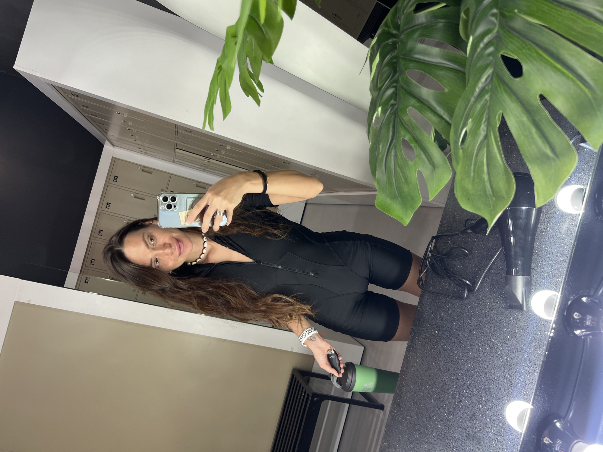 Woman takes locker room selfie with water bottle and phone