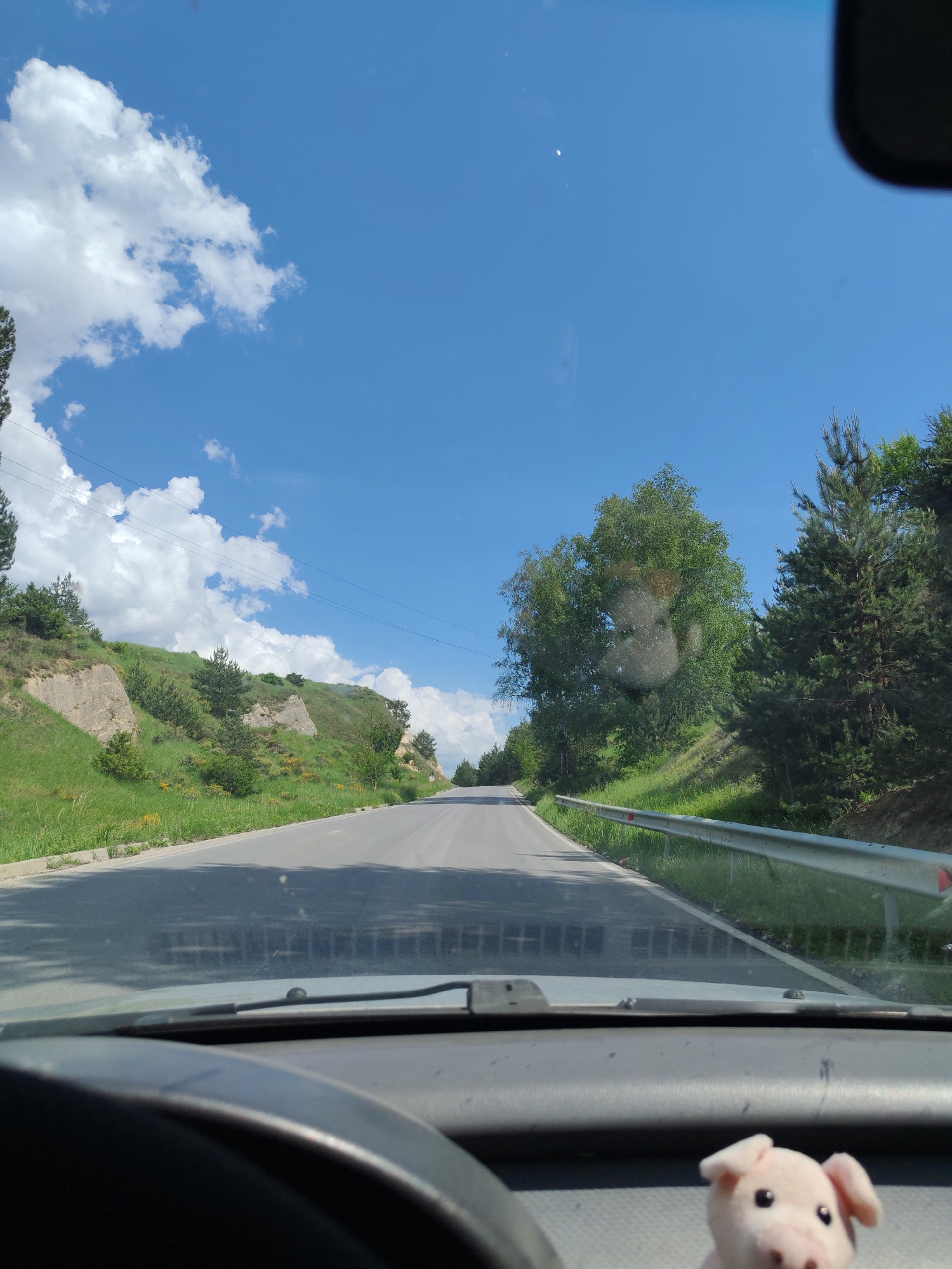 Vehicle drives scenic winding road through wooded hills