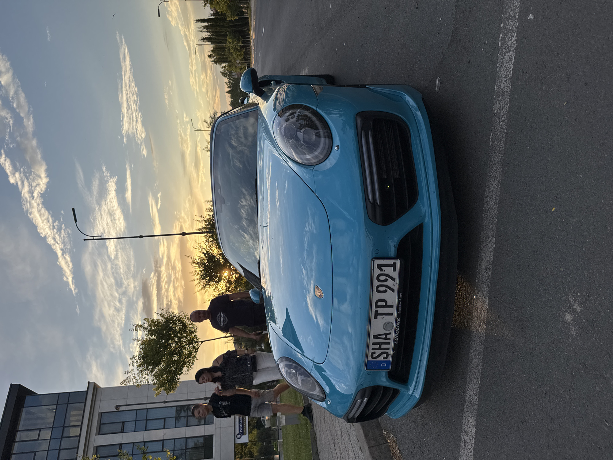 Blue Porsche draws attention on a Burgas street at sunset
