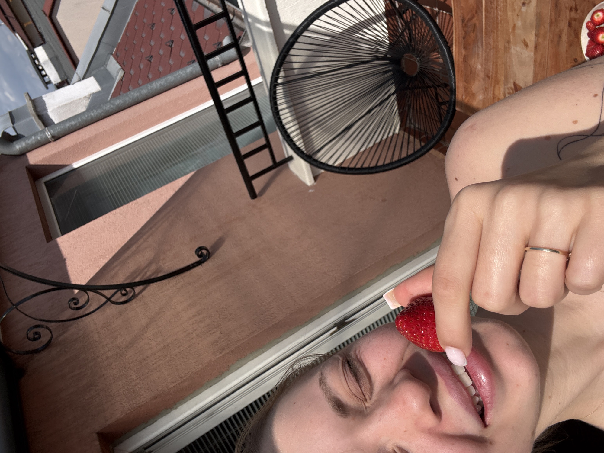 Person enjoys fresh strawberries on Sofia balcony overlooking city