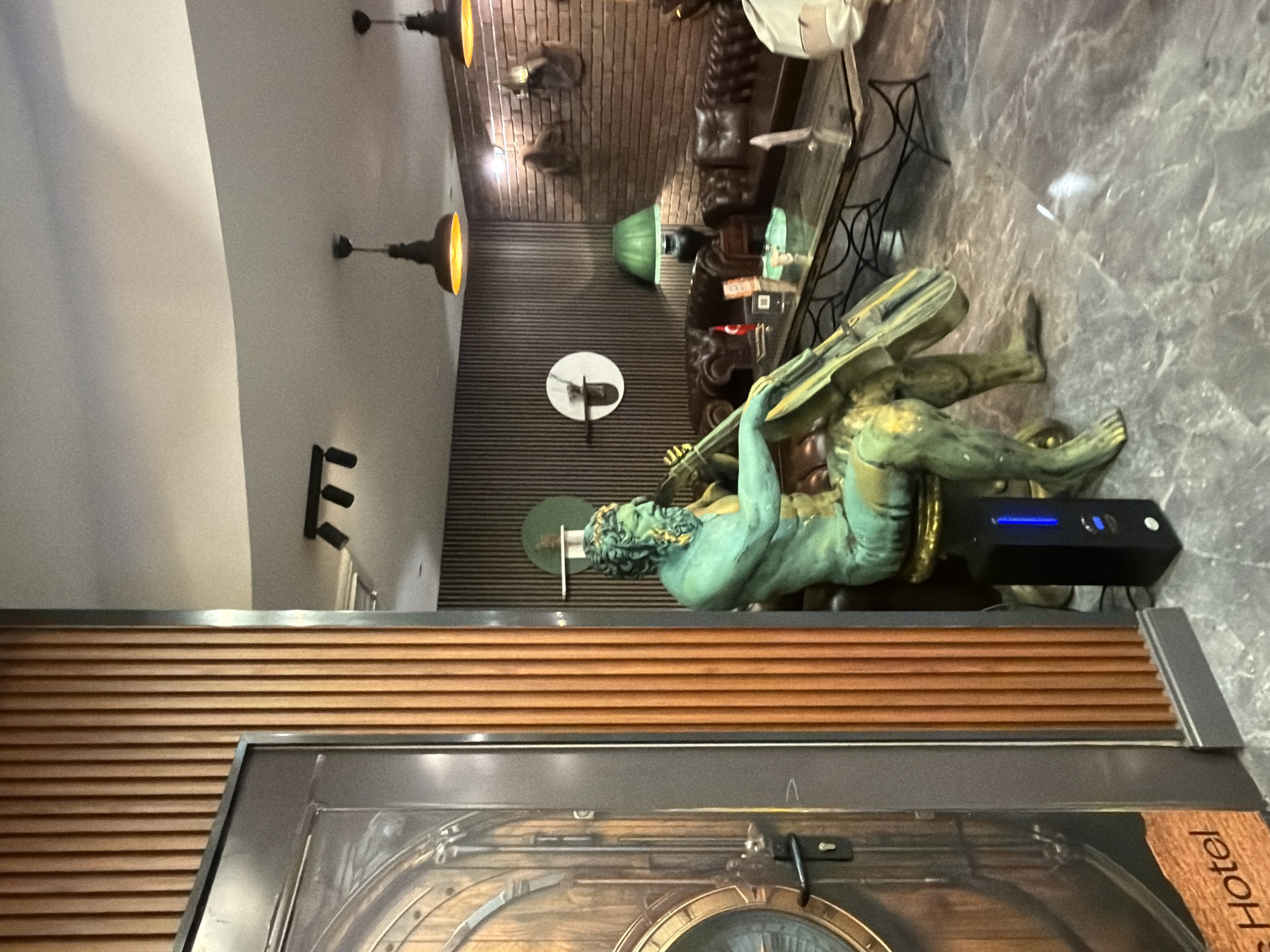 Ornate hotel lobby features large verdigris statue centerpiece