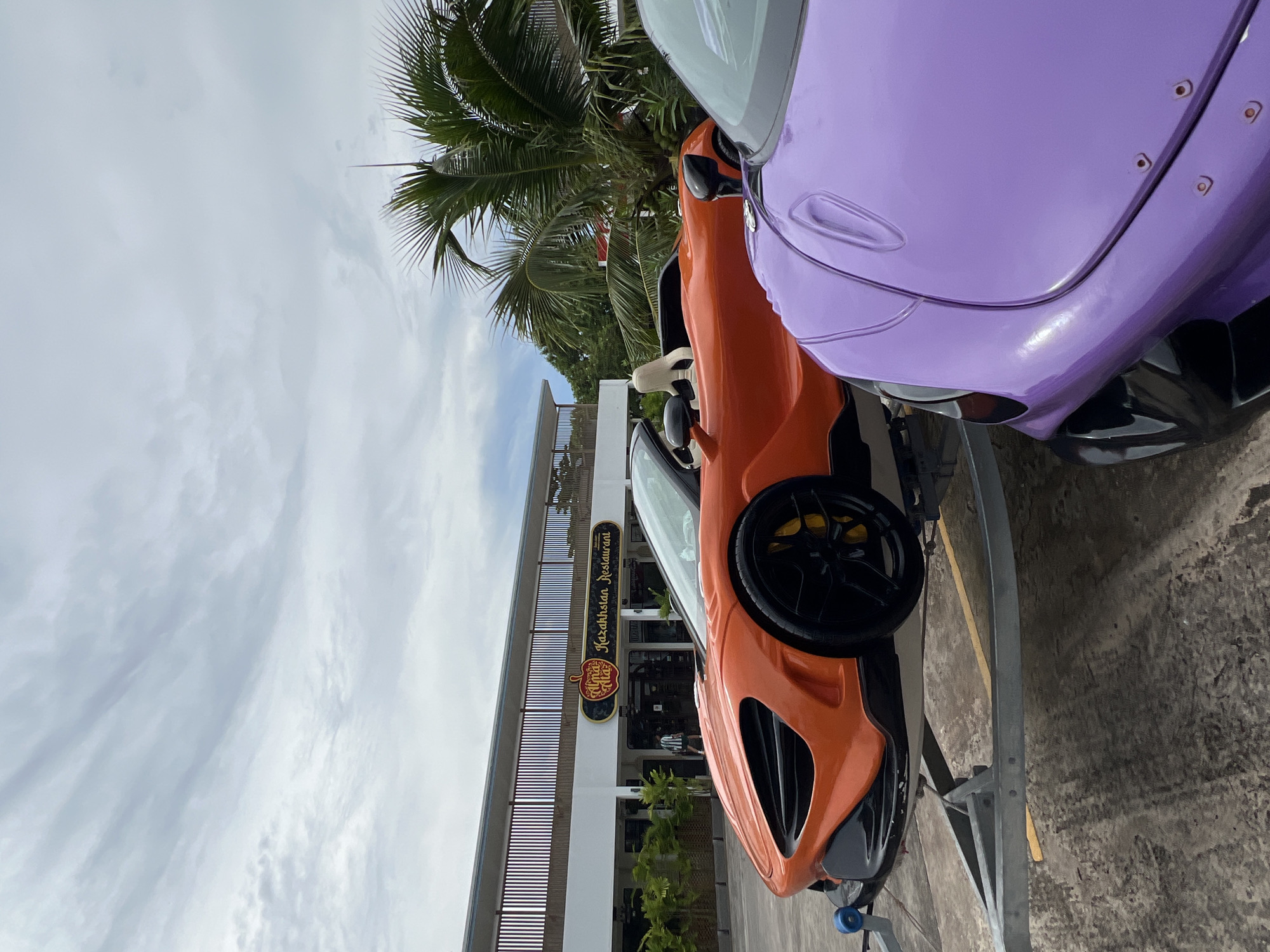 Two McLarens parked on trailers outside a Chalong restaurant