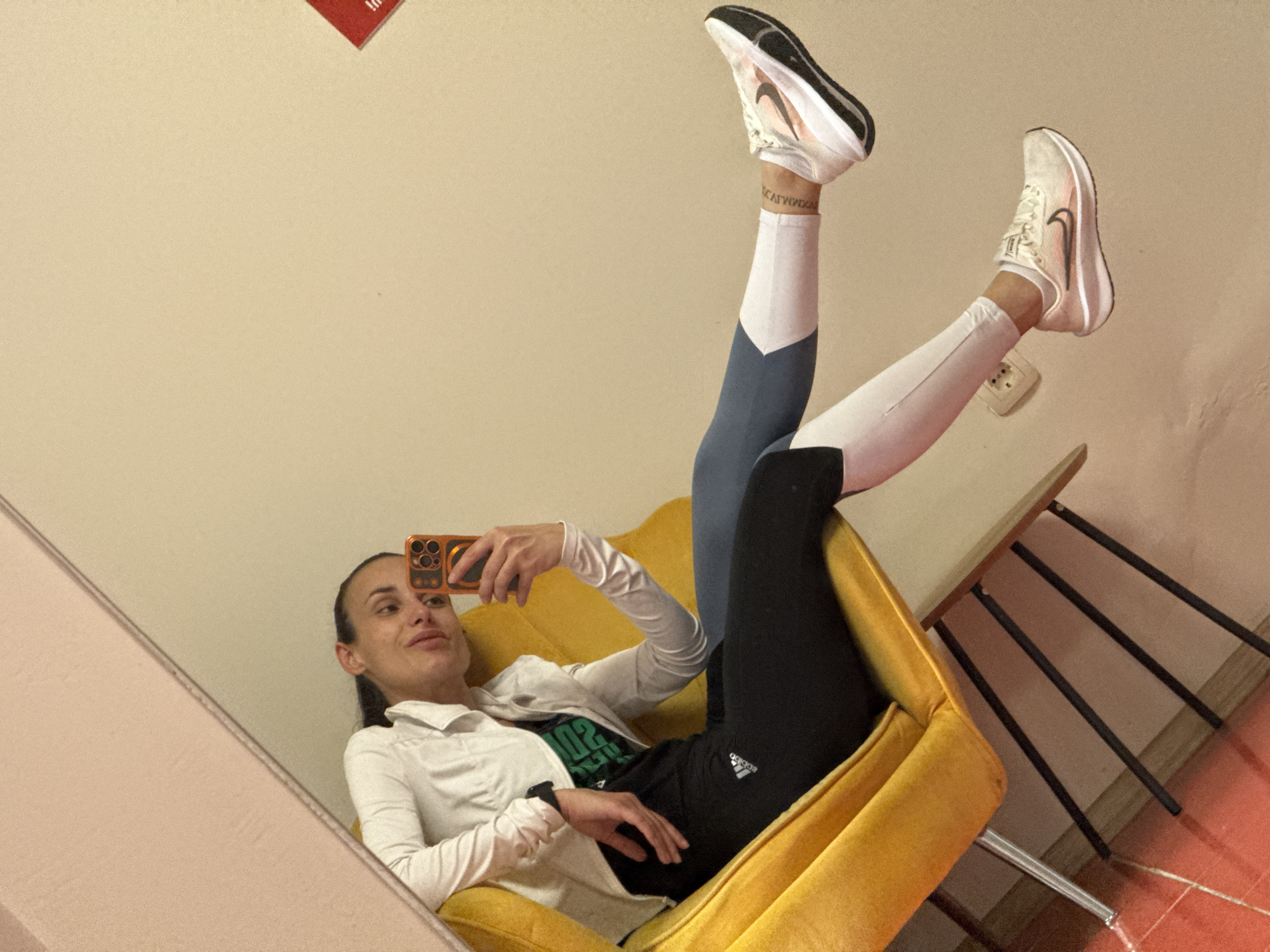Woman takes mirror selfies on yellow chair in Pleven