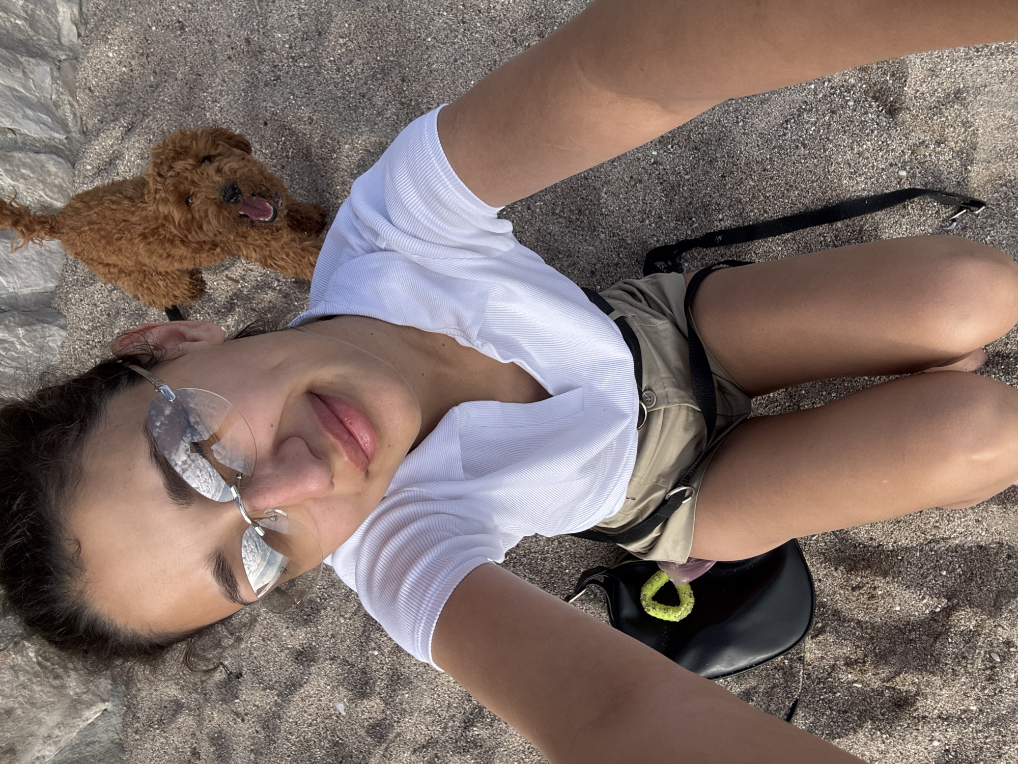 Woman takes selfie, dog plays at Montenegro beach