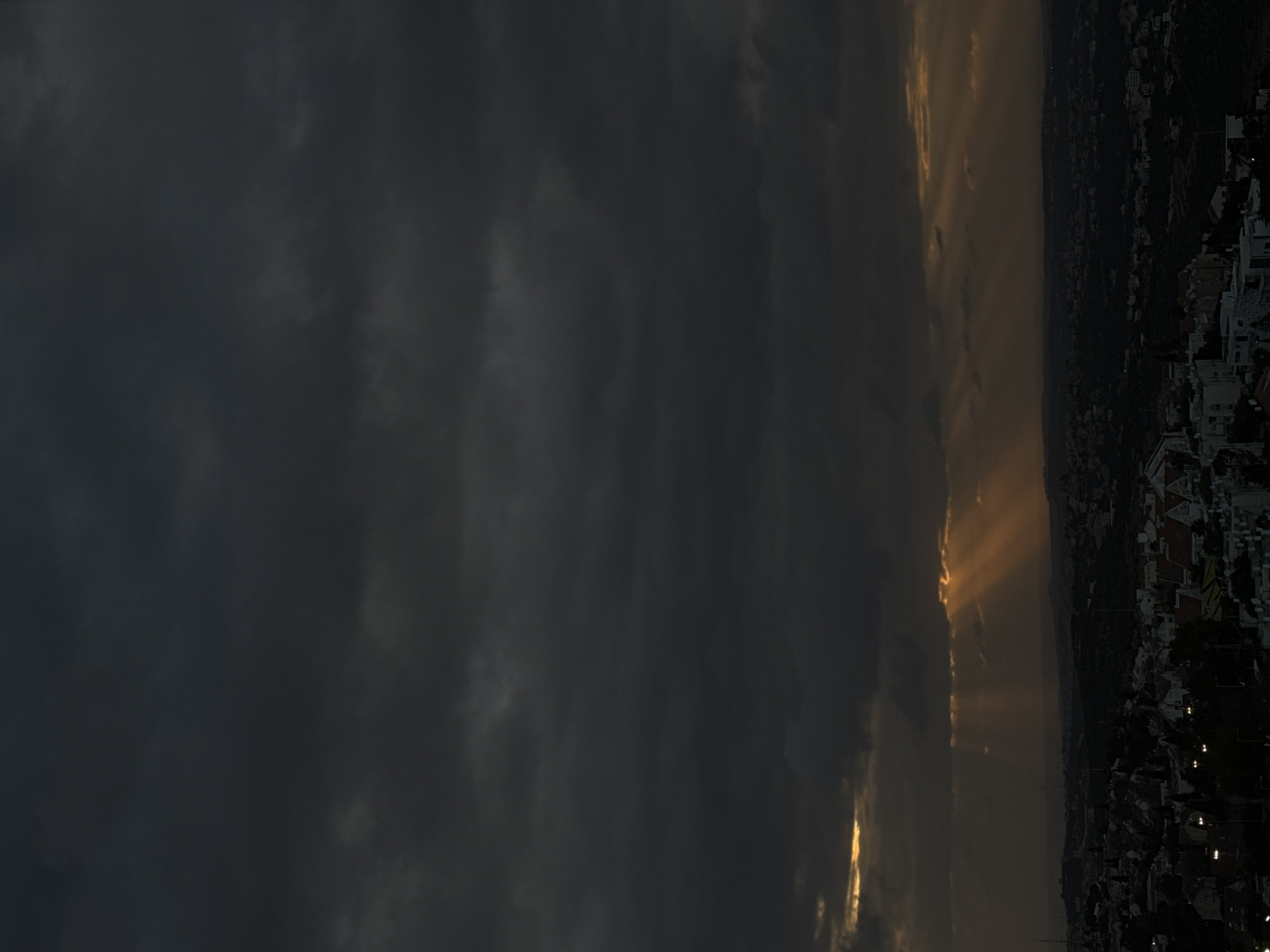 Sunlight breaks through dark clouds over urban landscape