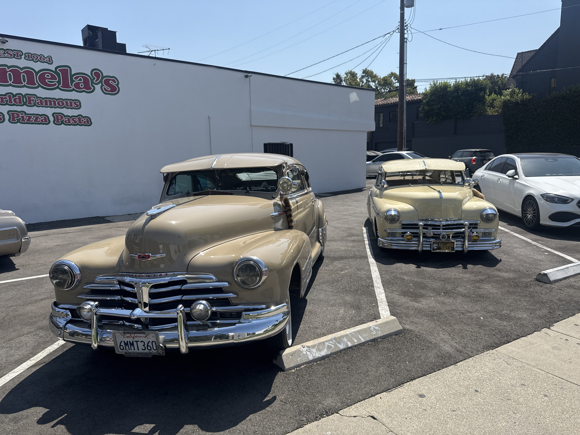 Classic American cars parked outside a vintage pizza joint