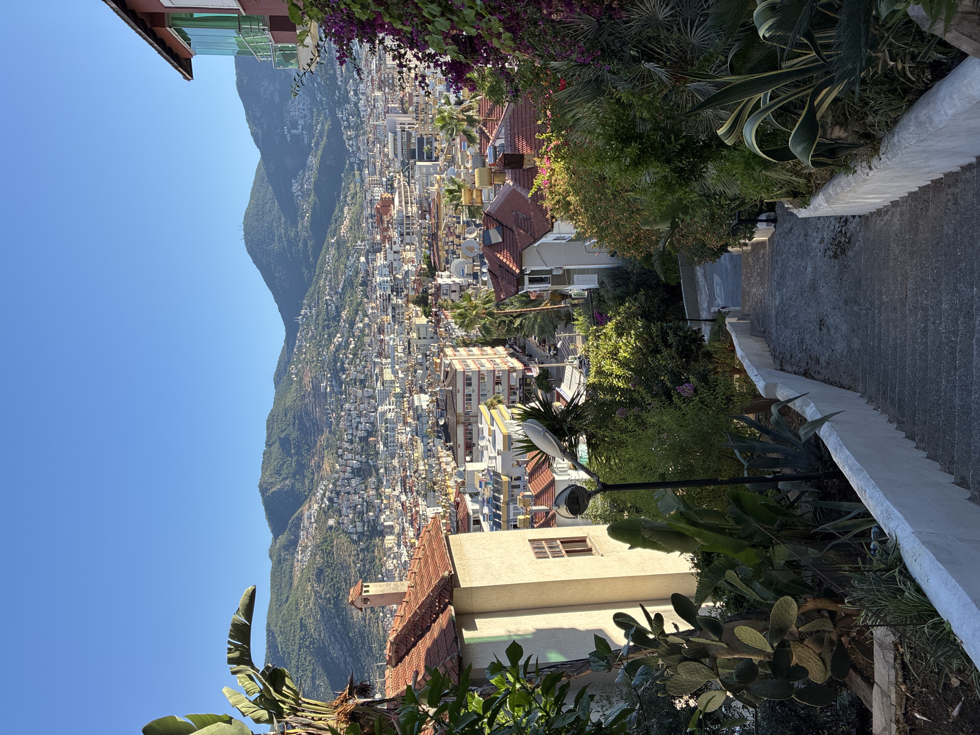 Alanya hillside staircase with bougainvillea and city views