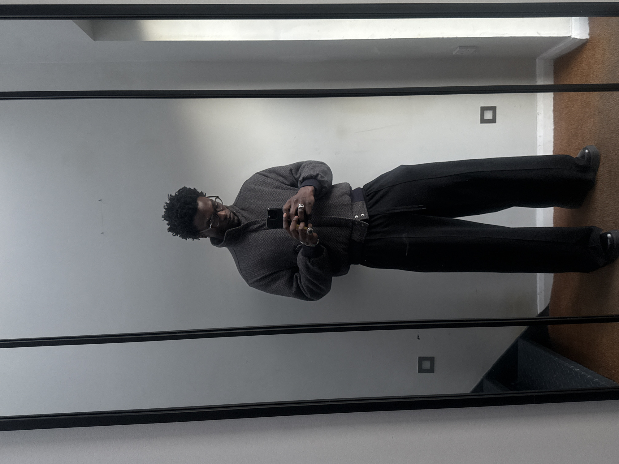 Person in herringbone jacket reflected in London mirror