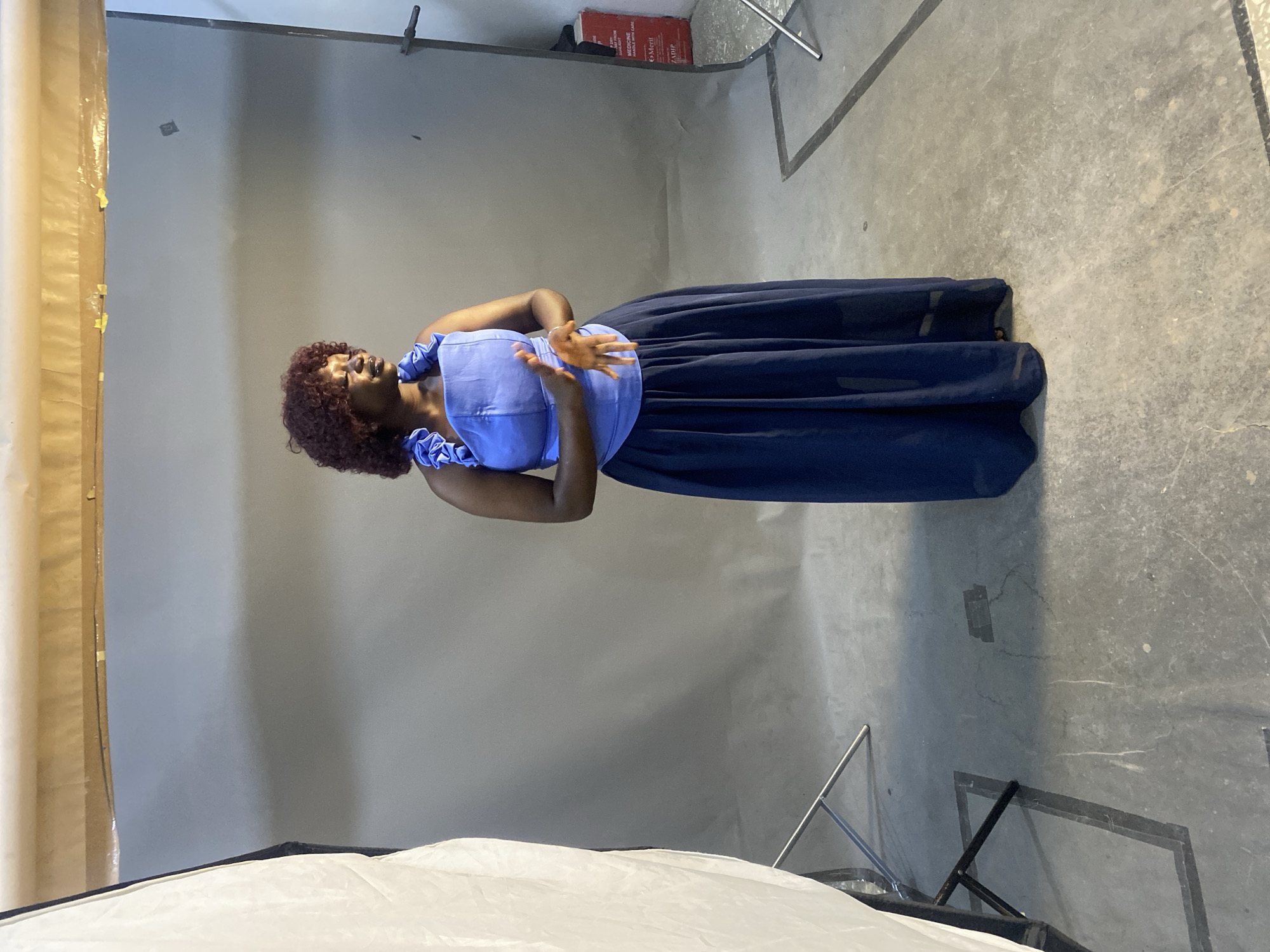 Studio portrait session in blue ruffled outfit against gray backdrop