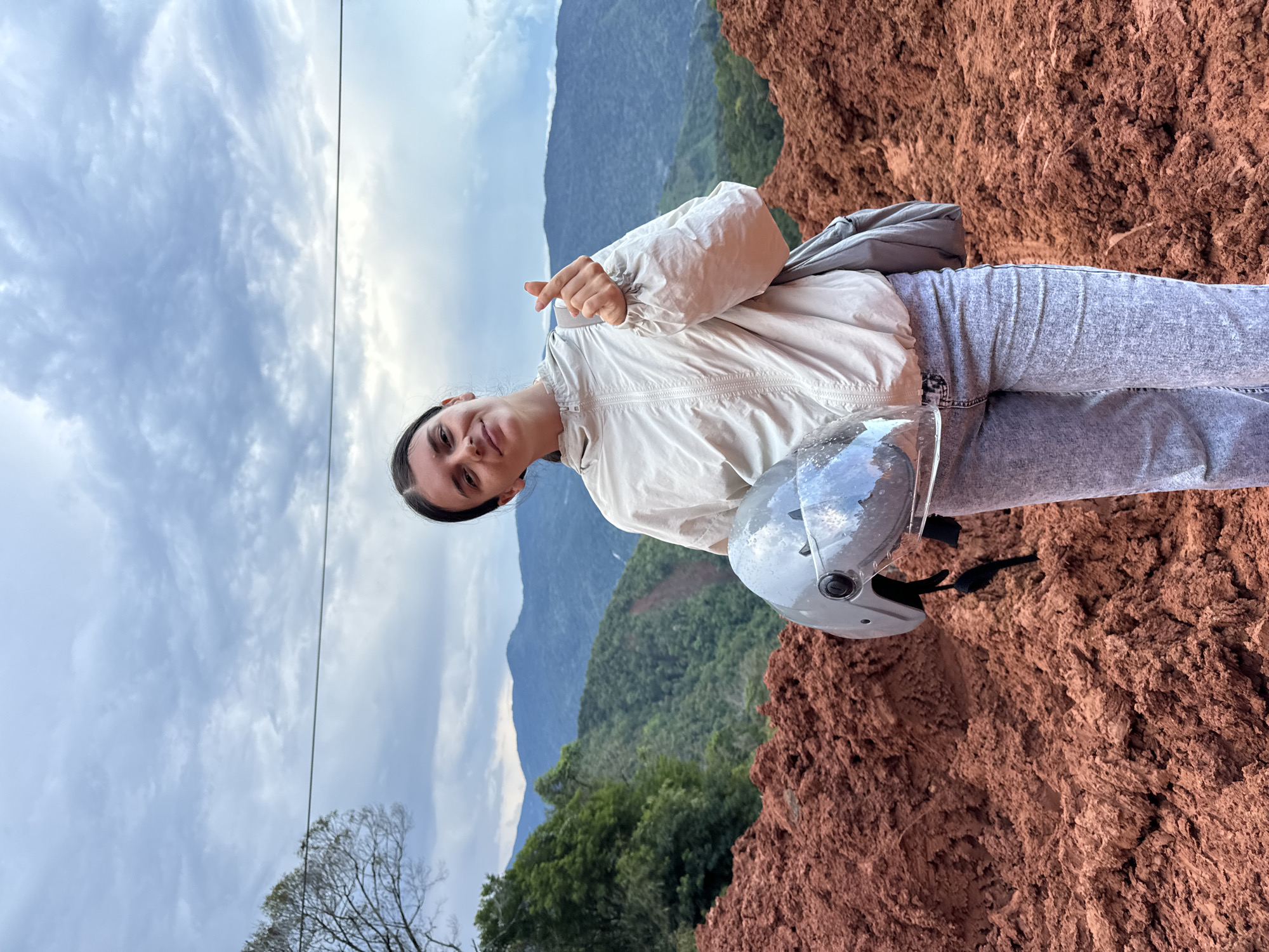 Woman motorcycles through muddy construction zone in rural Vietnam mountains