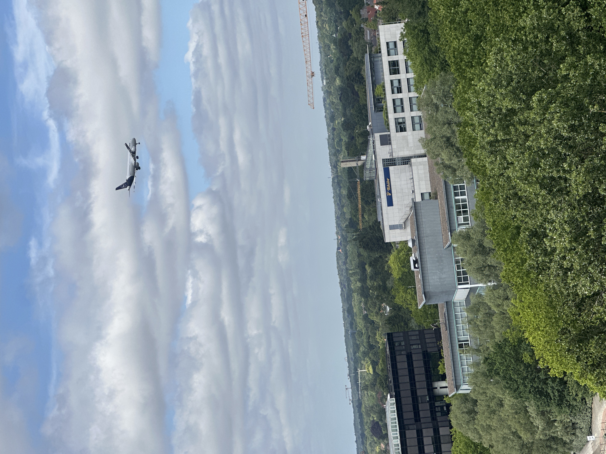 Drone views track a plane over Hamburg's mixed urban landscape
