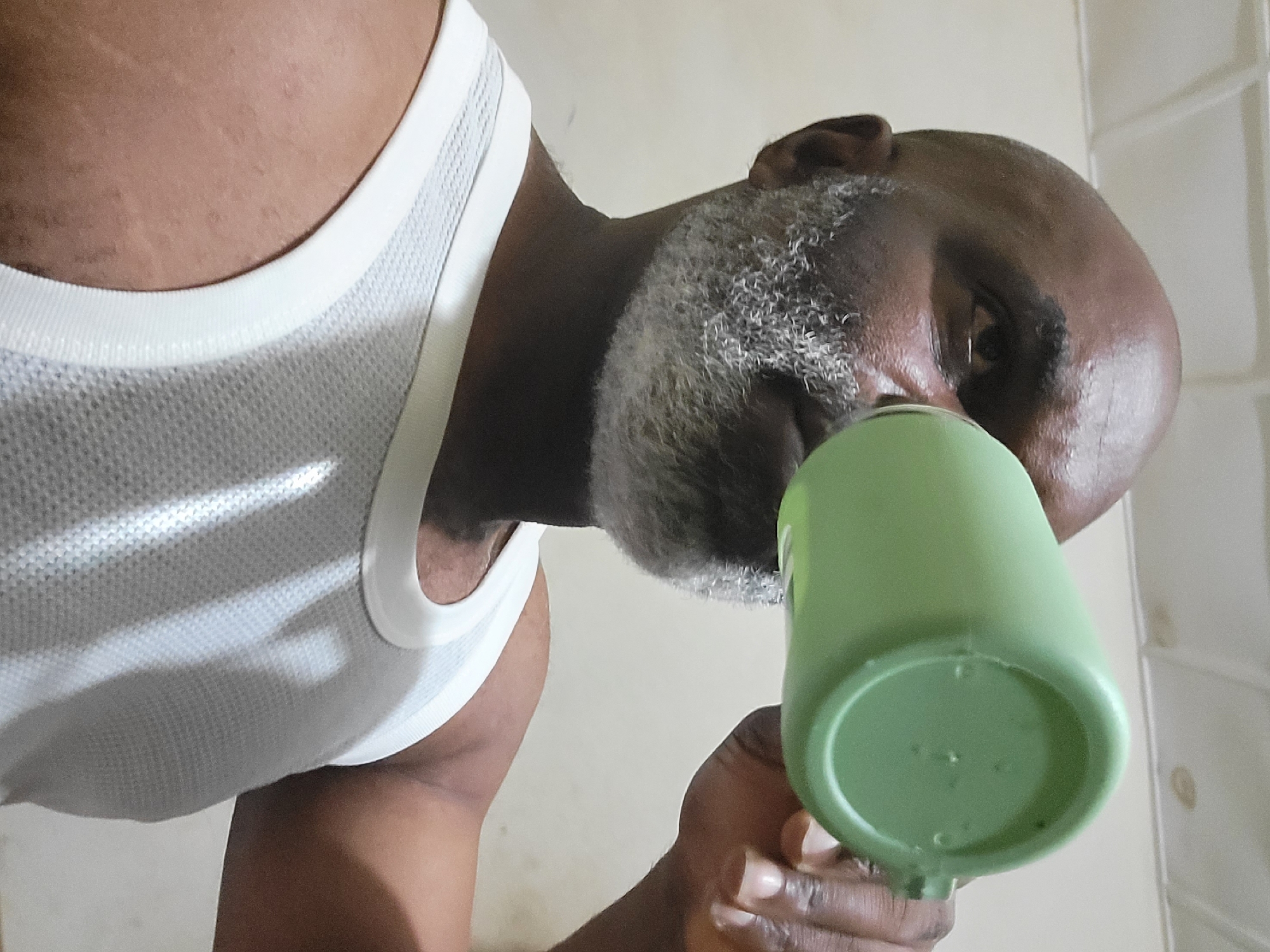 Man drinks from green cup in early morning hours