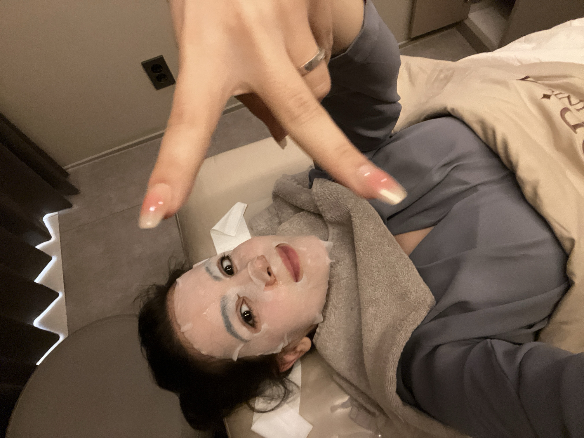 Person makes peace sign while resting in bed in Seoul