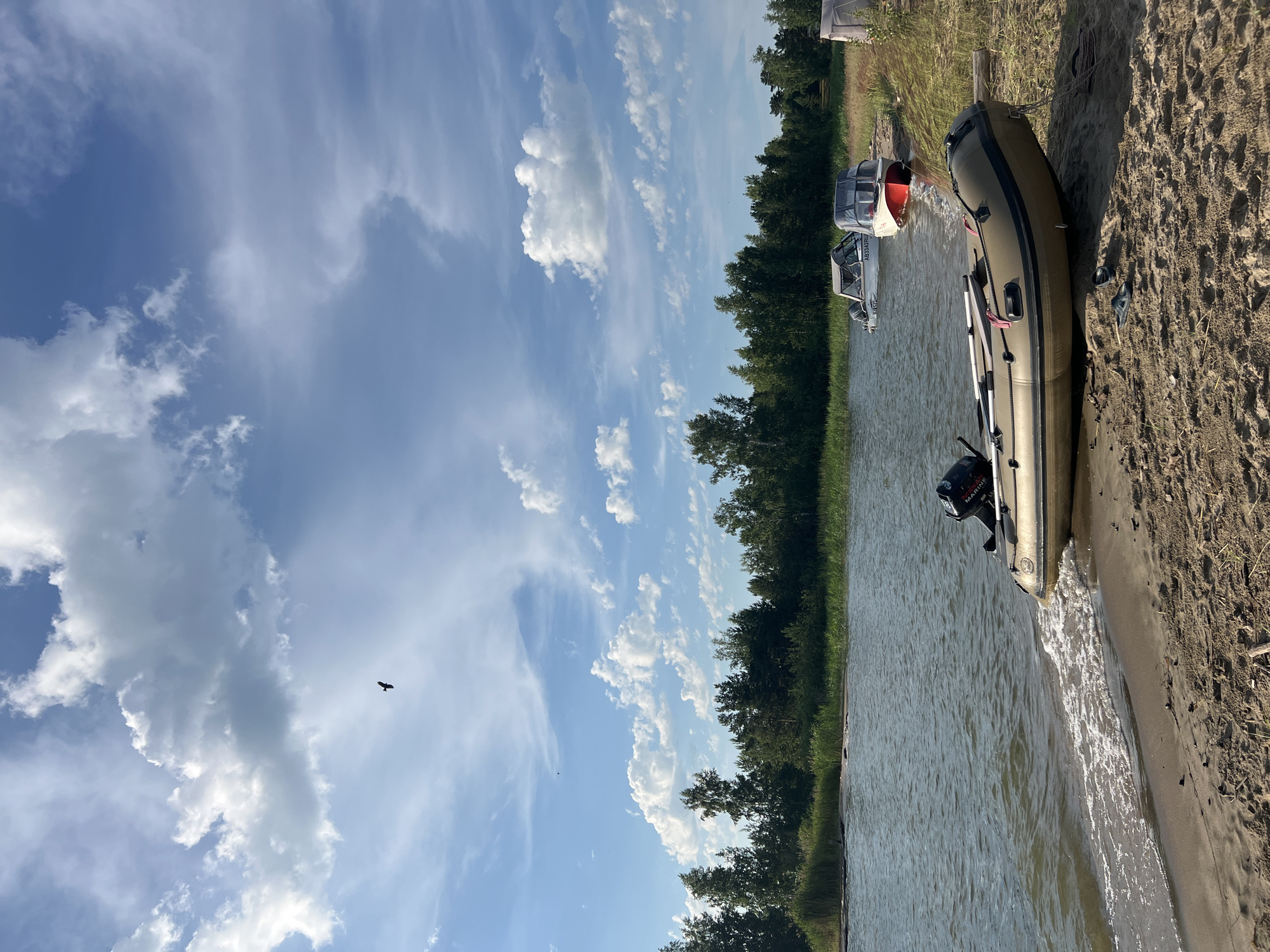 Boats on a calm Russian lakeshore under summer skies