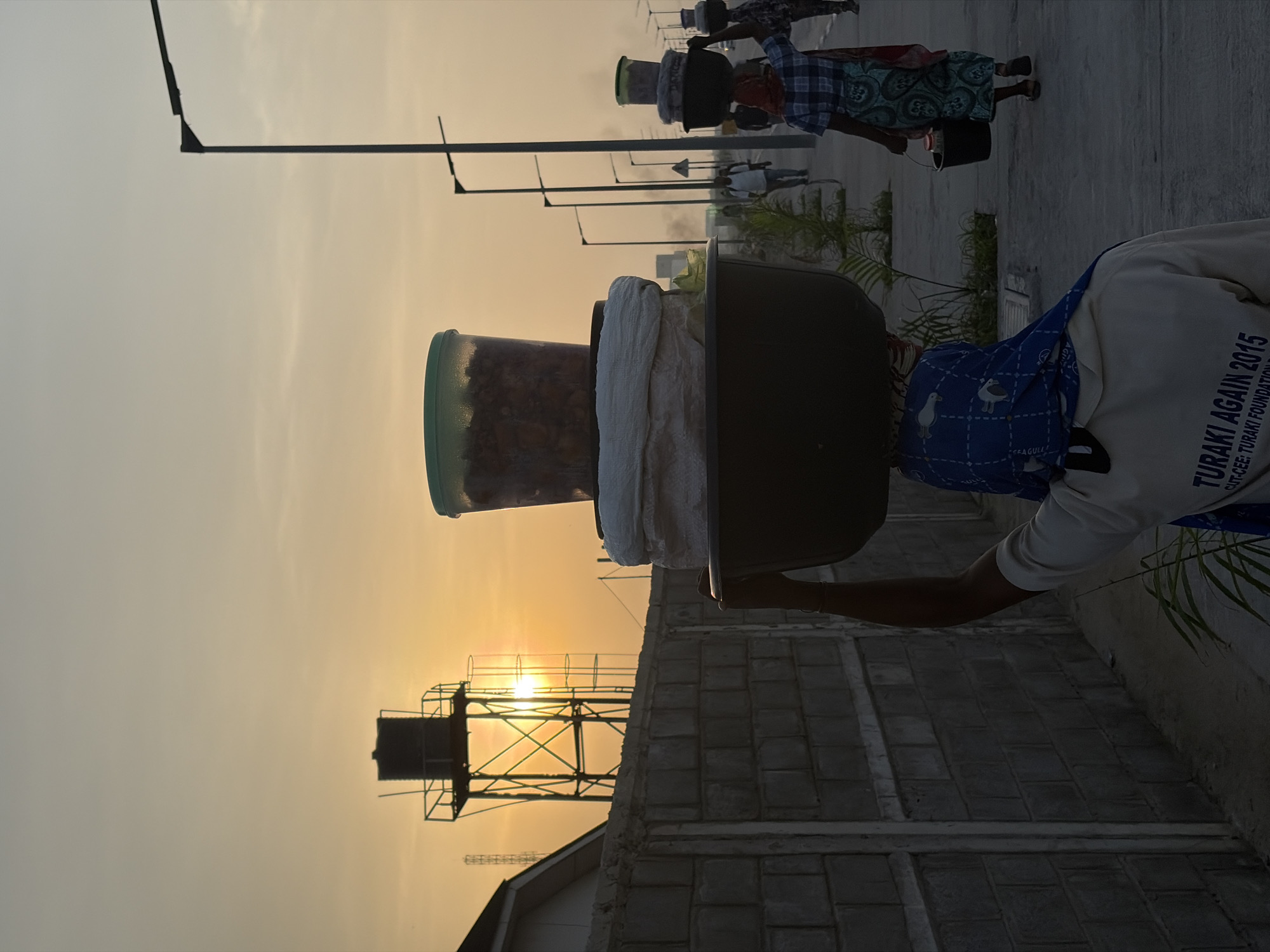 Women carry goods at sunrise in Nigerian village