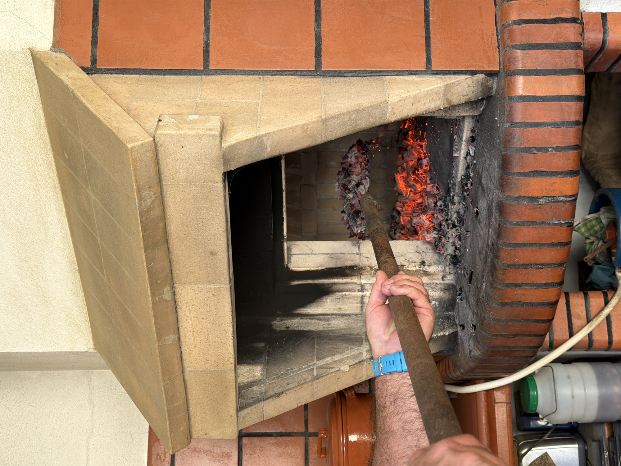 Person tends wood-fired brick oven in Vila Real