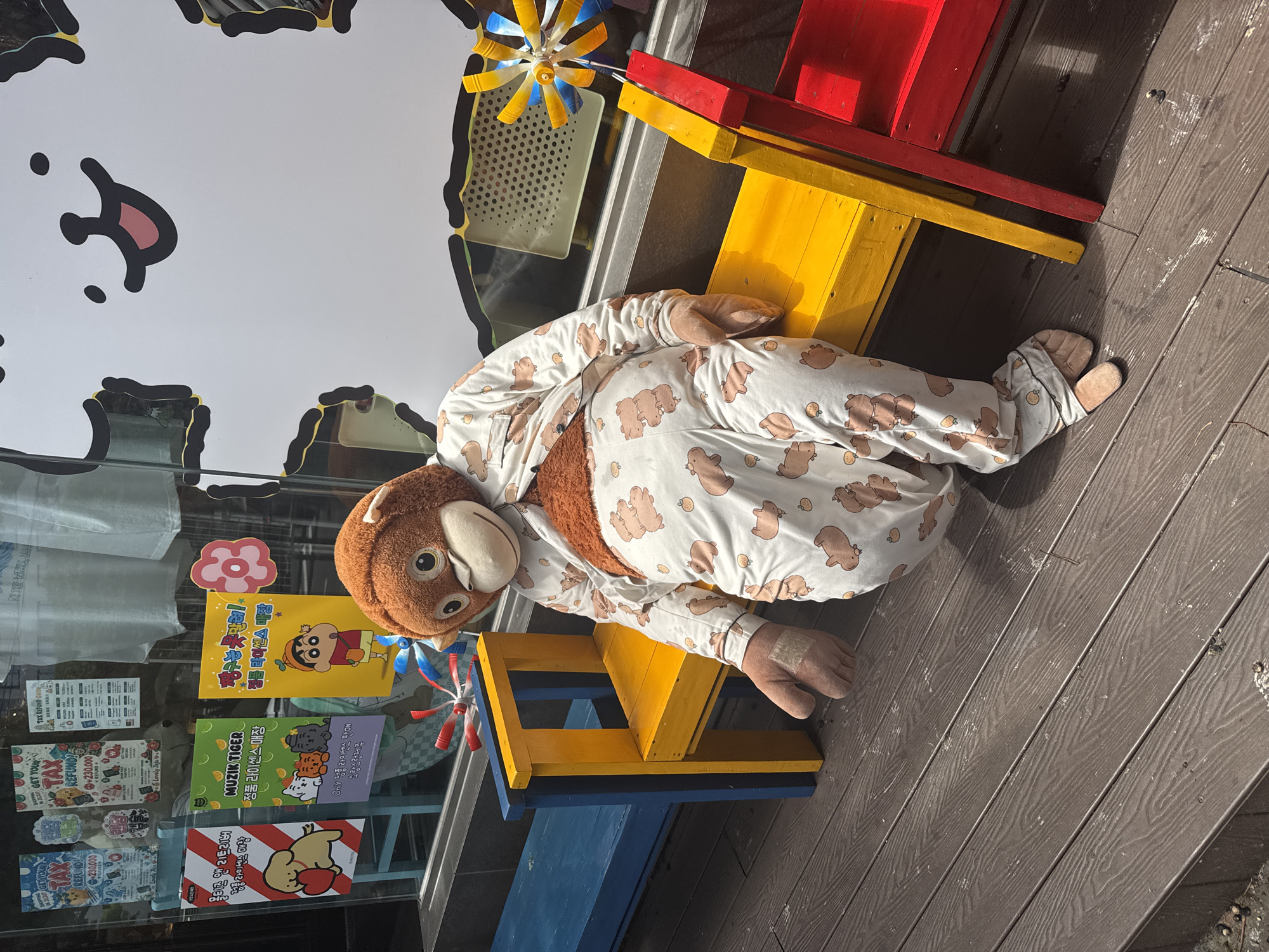 Pajama-clad stuffed monkey on a yellow bench in Jeju