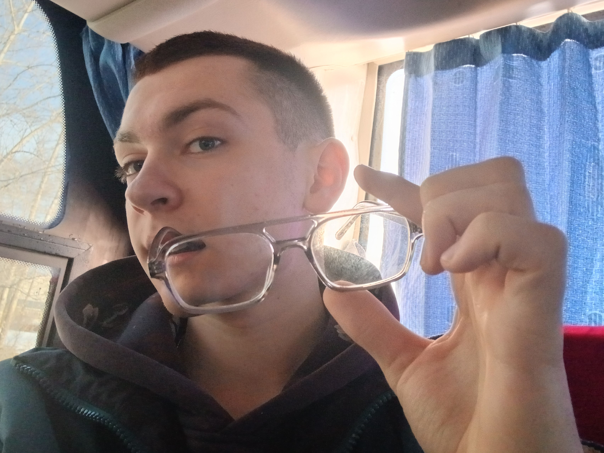 Young man holds glasses in mouth on Berezniki bus
