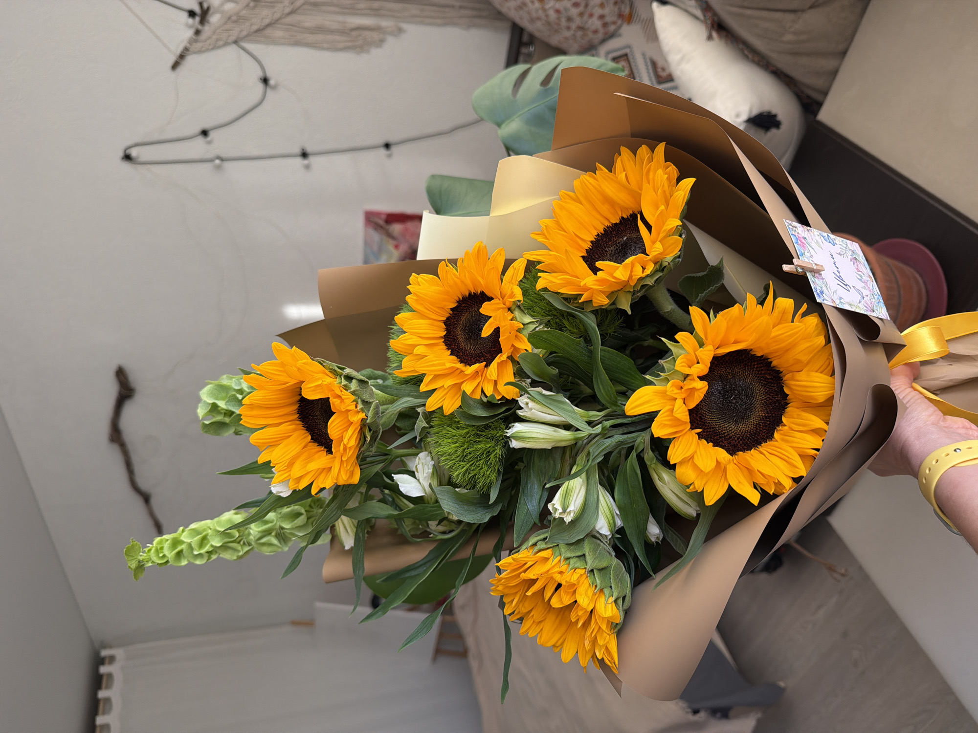 Person holds sunflower bouquet with yellow watch observed