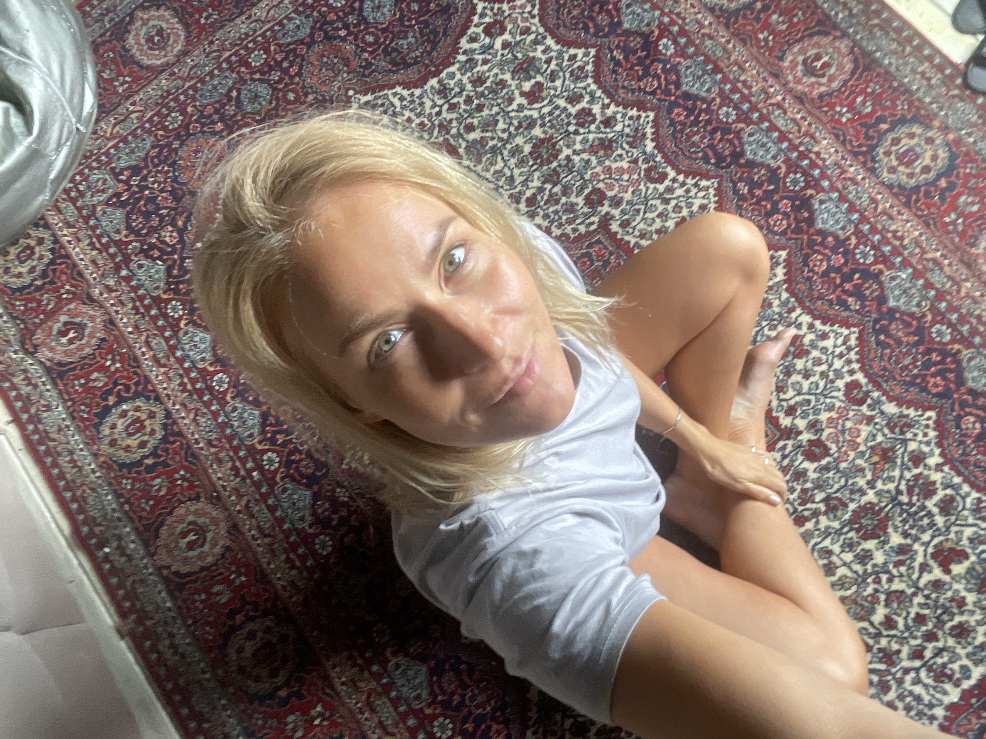 Woman poses on rug, near window in Baranovka