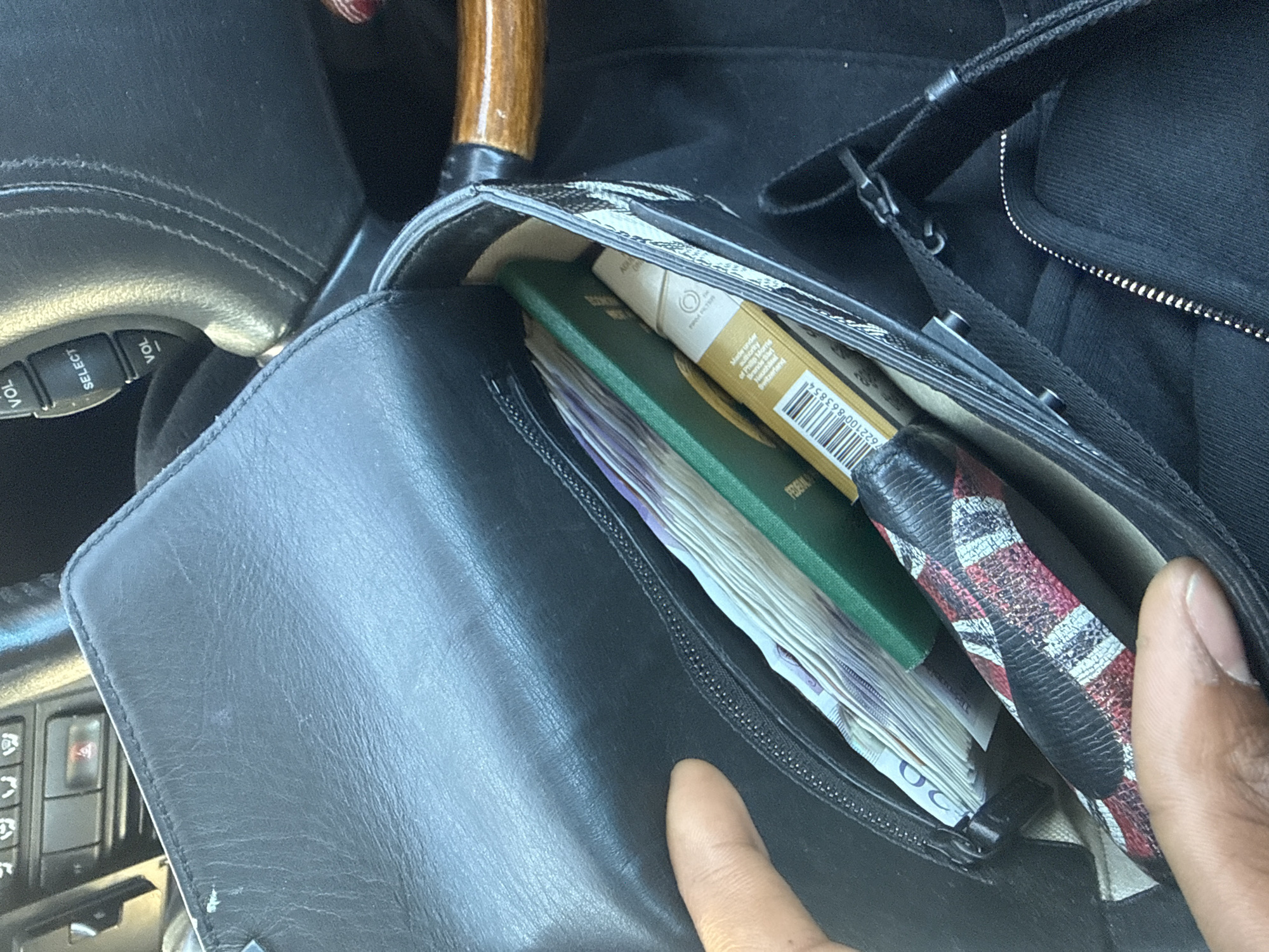 London resident examines black leather bag contents in vehicle