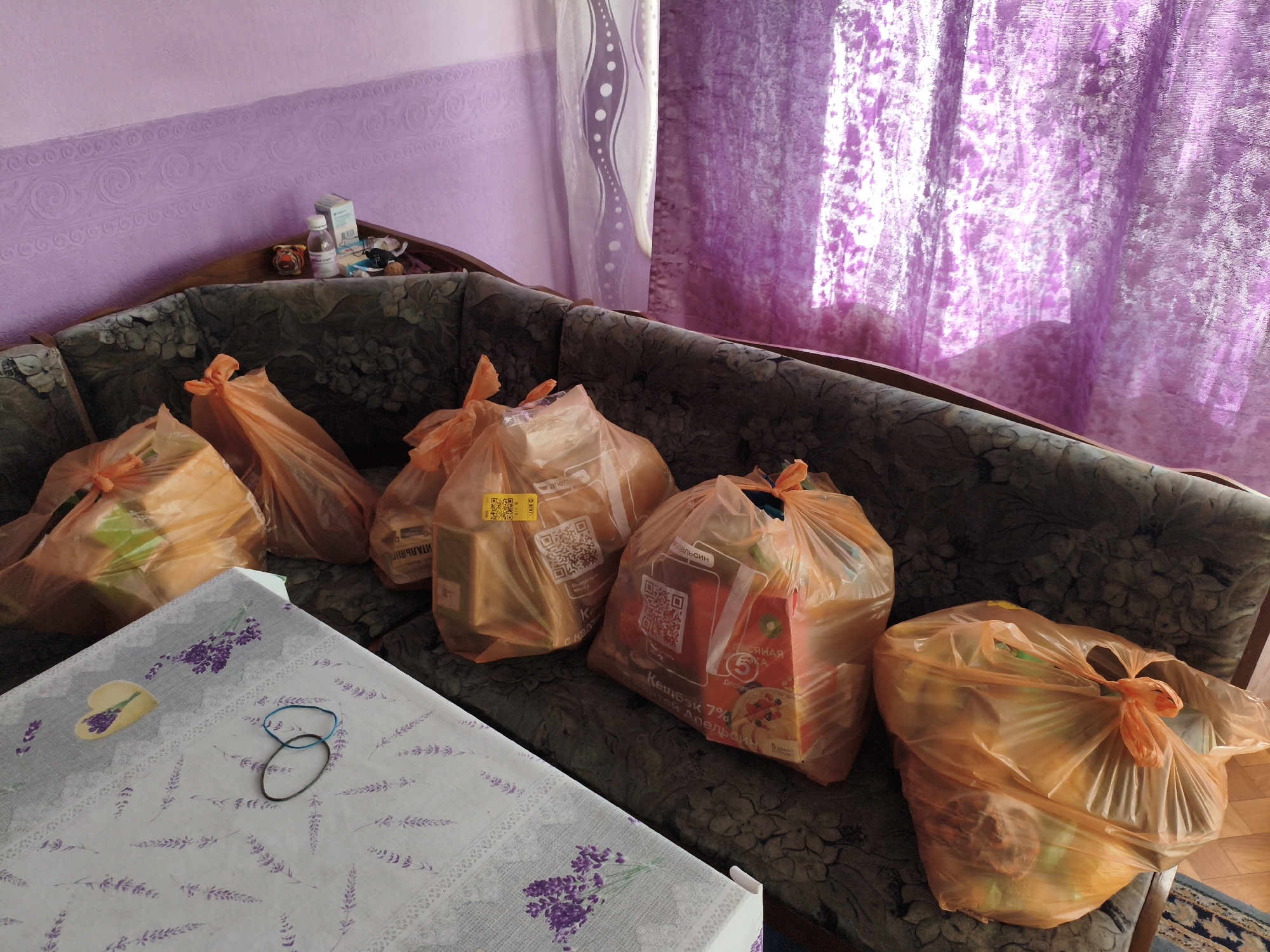 Floral couch piled with orange grocery bags in a purple room