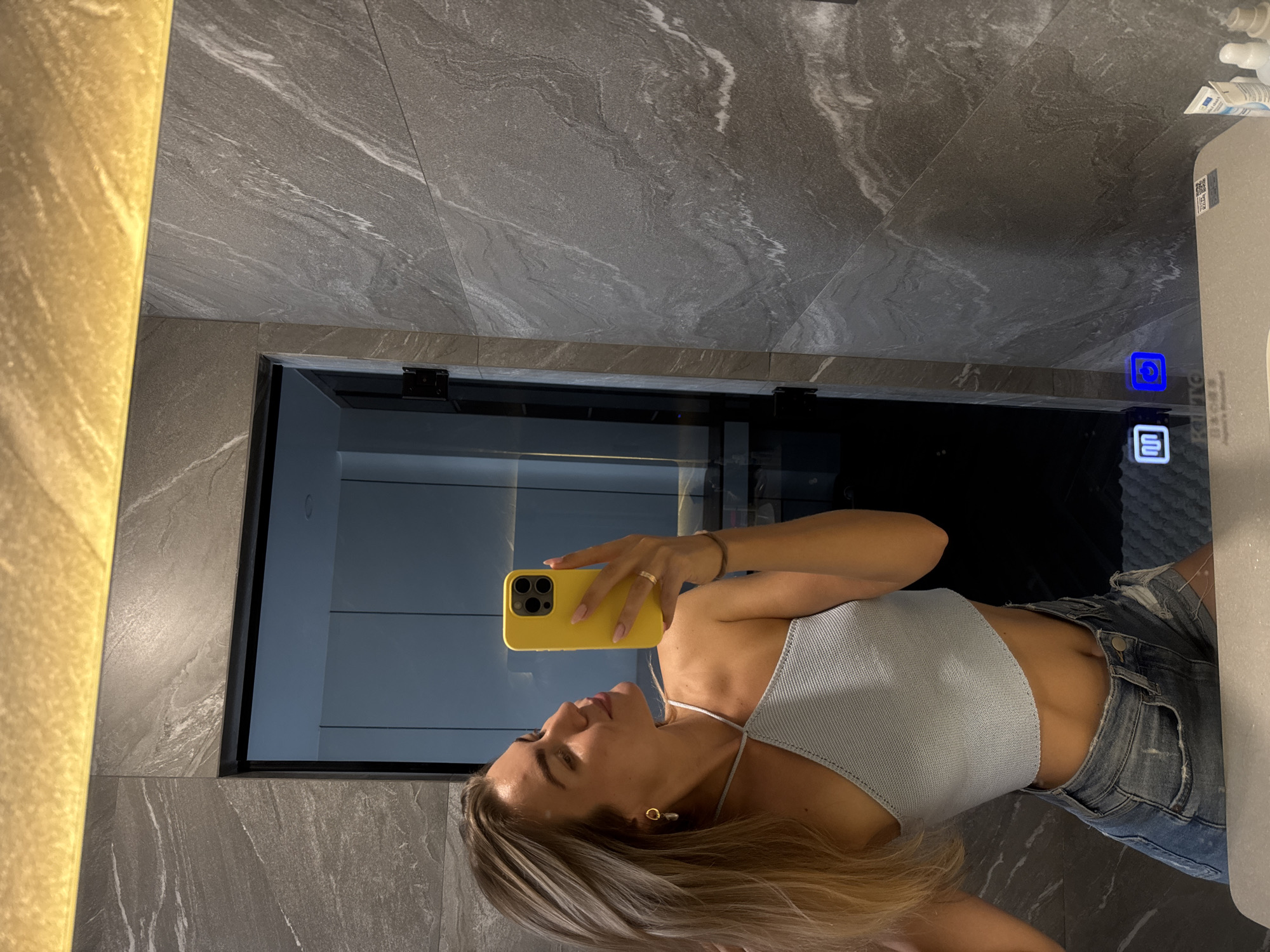 Person takes bathroom selfie with yellow phone