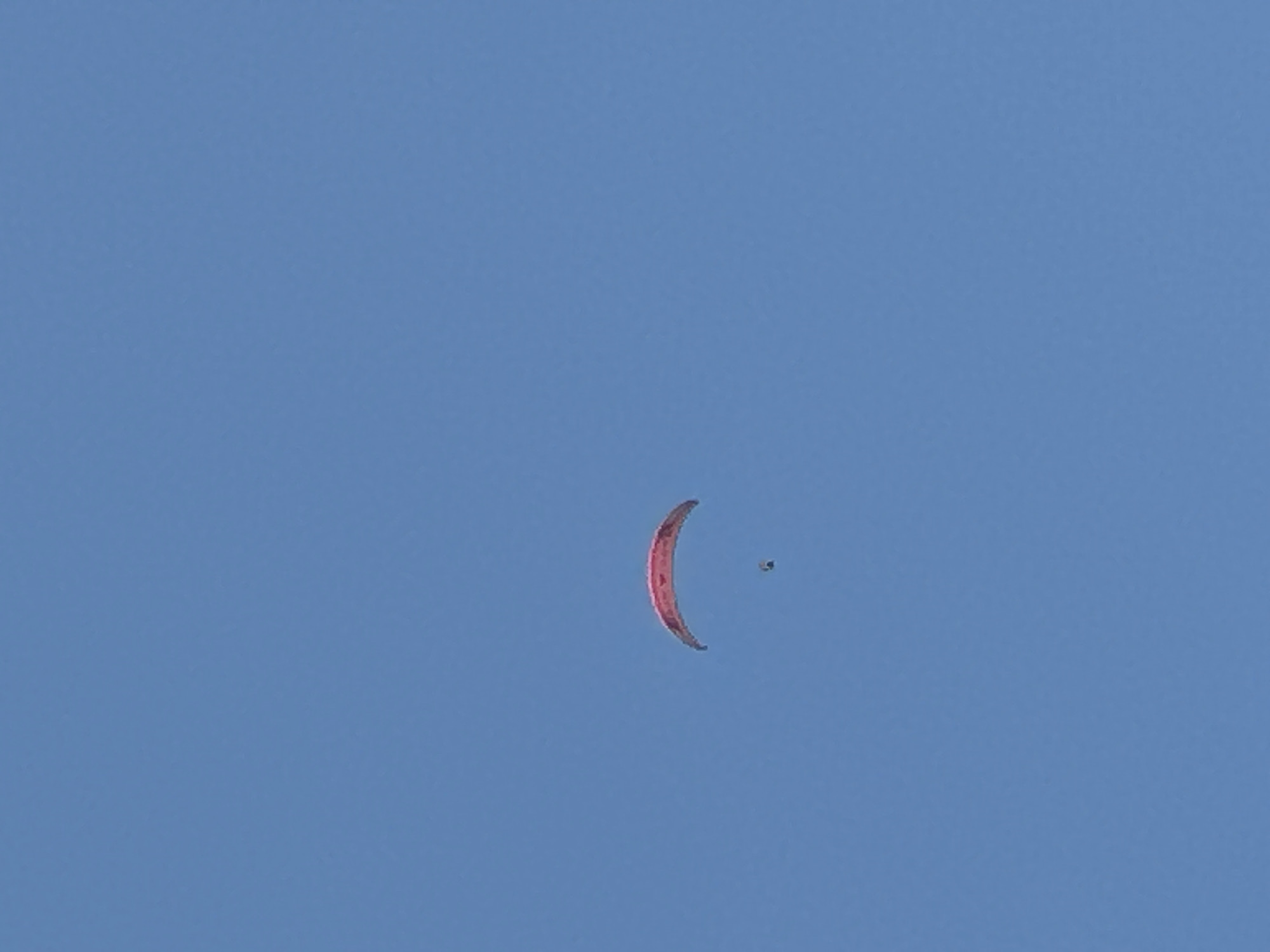 Paragliders soar over Rafailovići's green hills on a clear day
