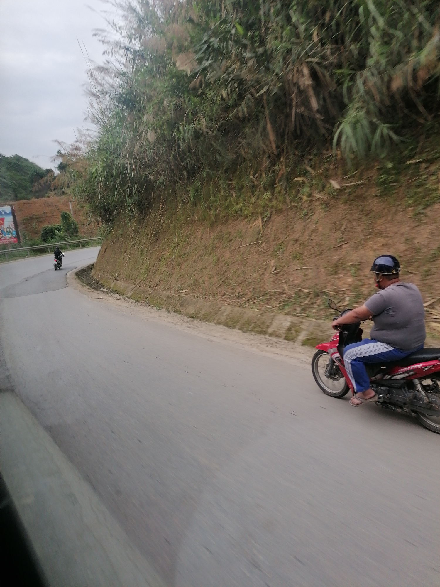 Two people spotted on curved hillside road in Vietnam