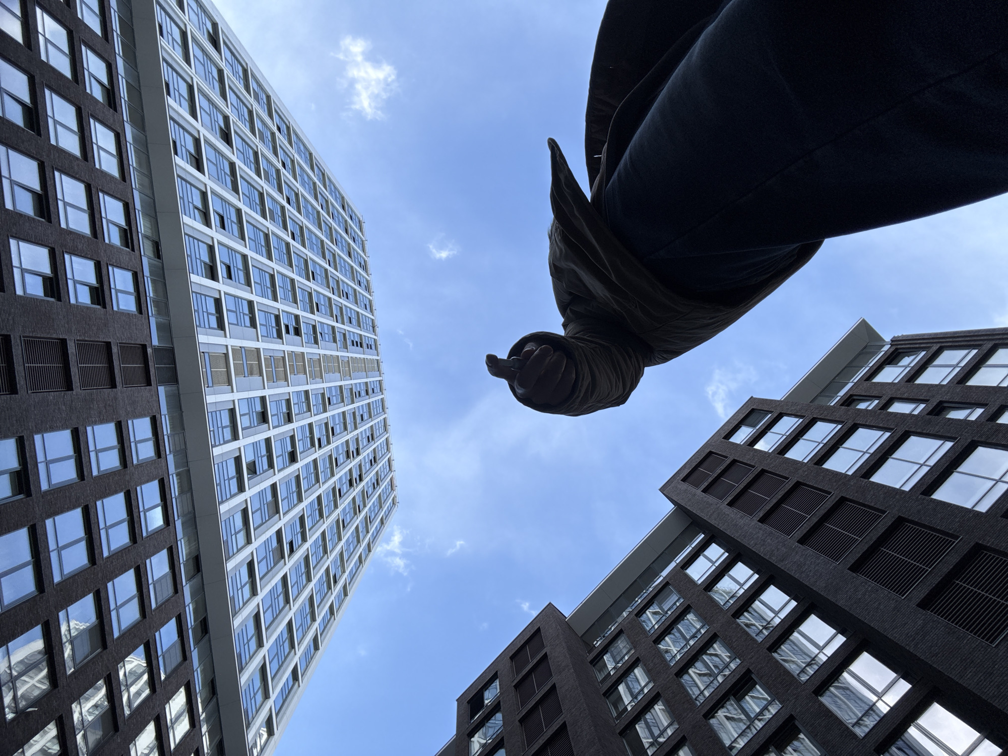 Person gazes skyward in Moscow courtyard amid modern towers
