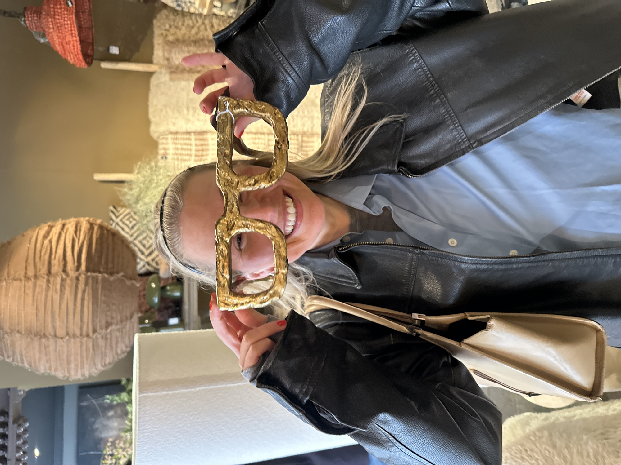 Woman poses with novelty gold D-shaped glasses in London