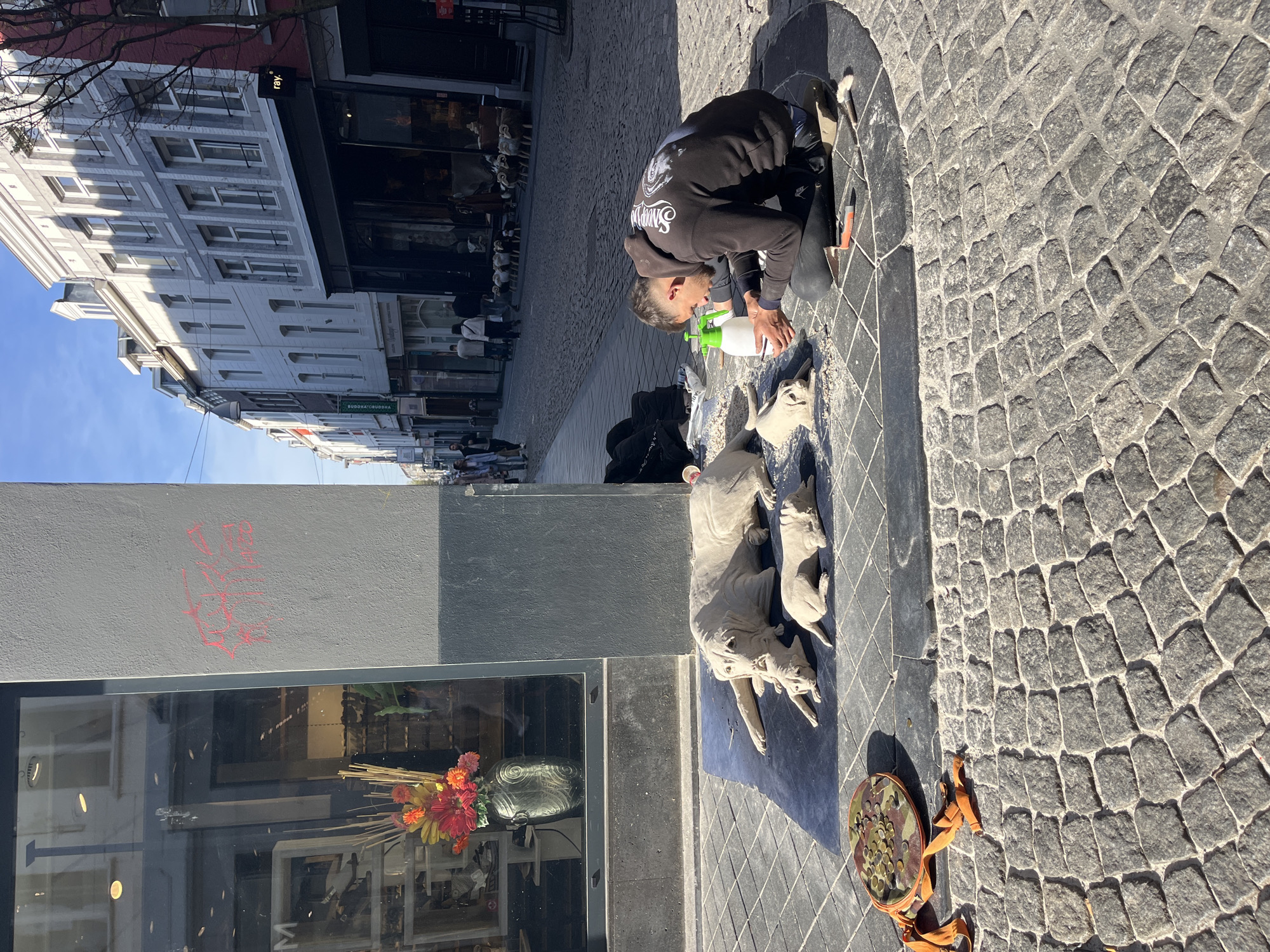 Man cleans stone dog sculpture on Maastricht street